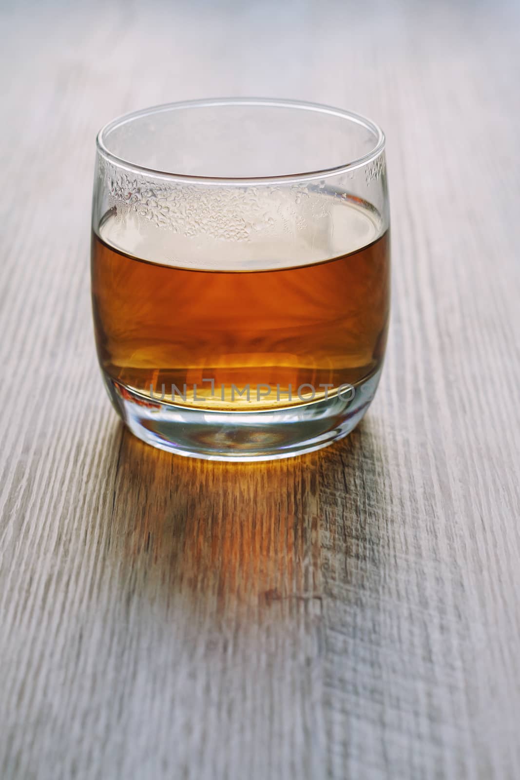 Hot tea in a glass, on a wooden table, in backlight.