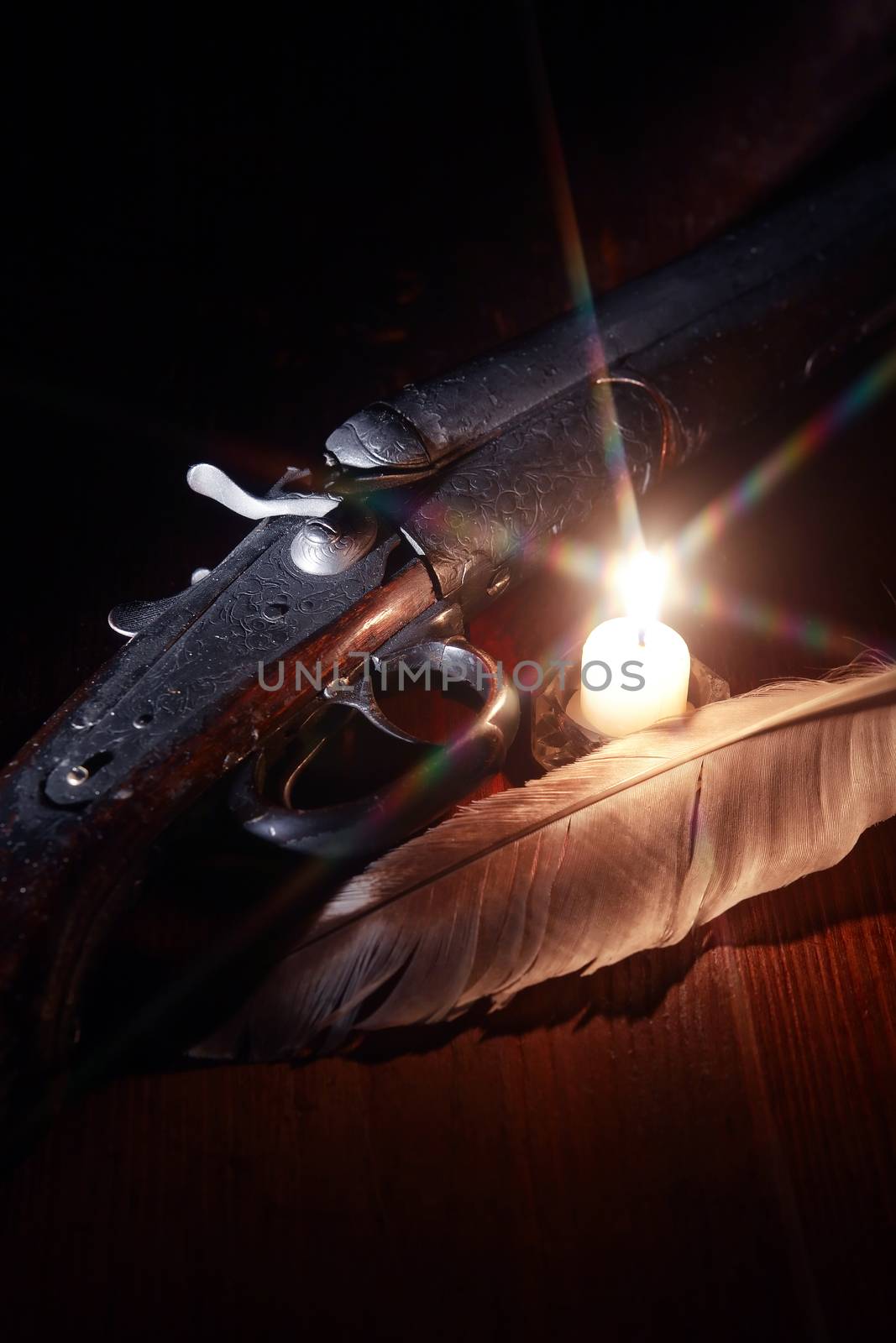 Ancient hunting shotgun closeup on wooden board near lighting candle
