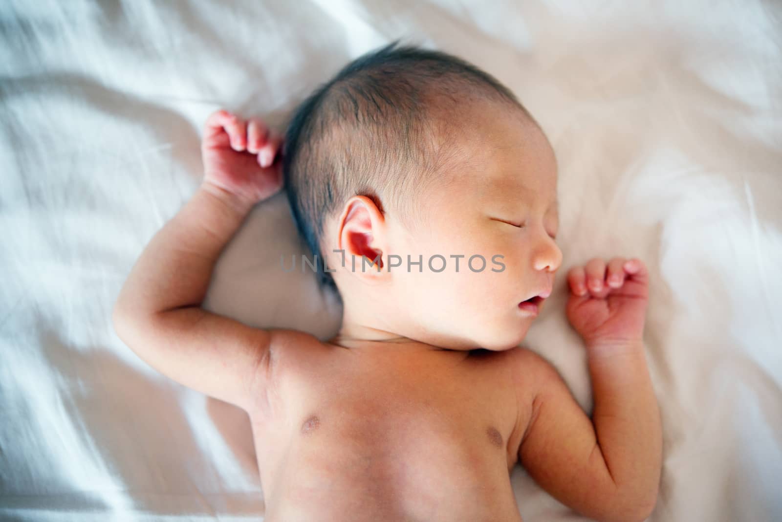 Sleeping Asian newborn baby on a blanket, 7 days old.