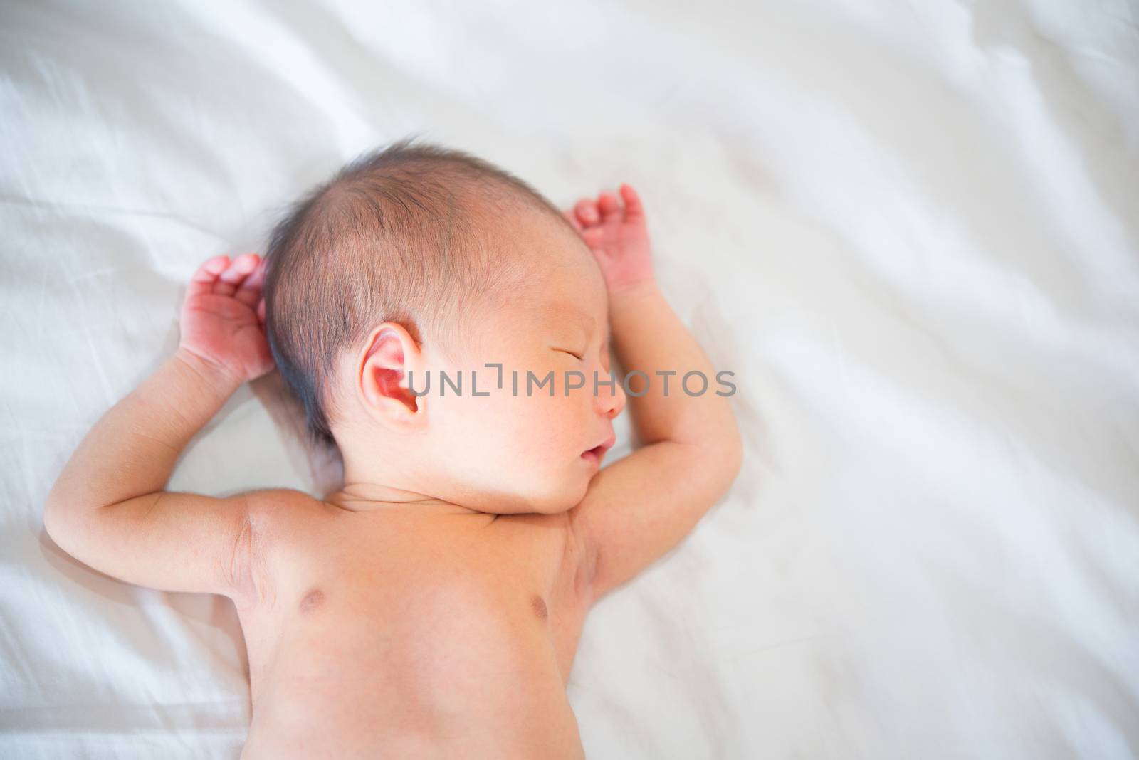 Asian newborn baby boy sleeping with tenderness in white blanket, 7 days old.