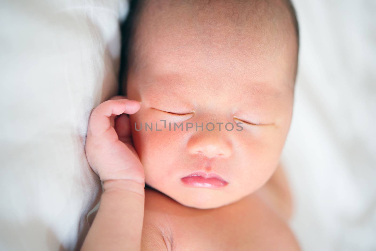 Asian newborn baby sleeping in bed.