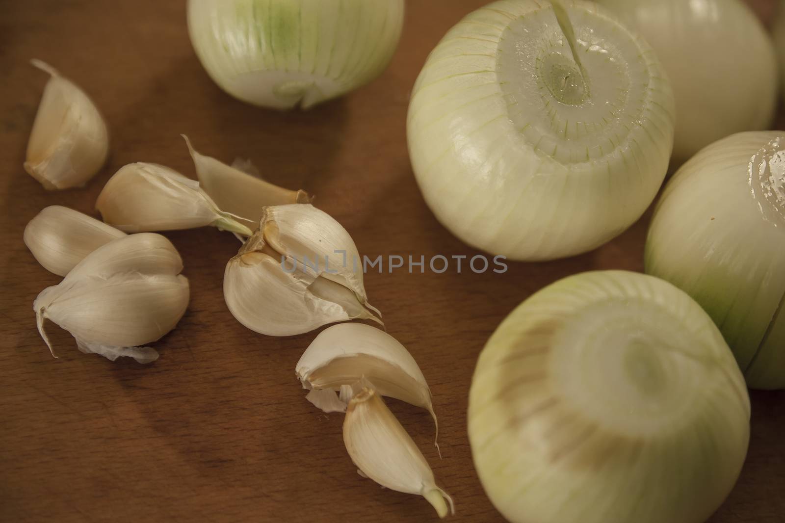 Garlic and onions on wooden board, prepared for cooking.
