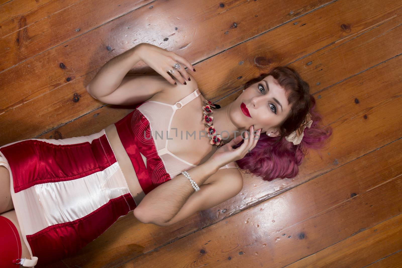 Girl with red vintage lingerie on a wooden floor.