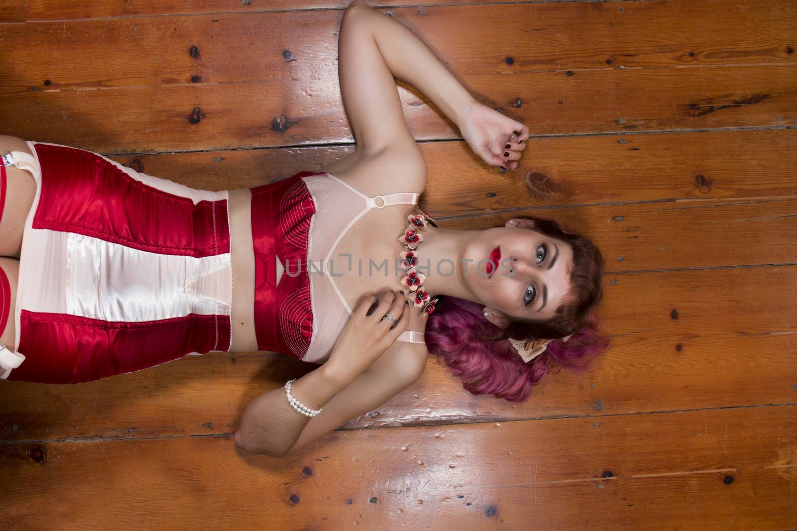 Girl with red vintage lingerie on a wooden floor.