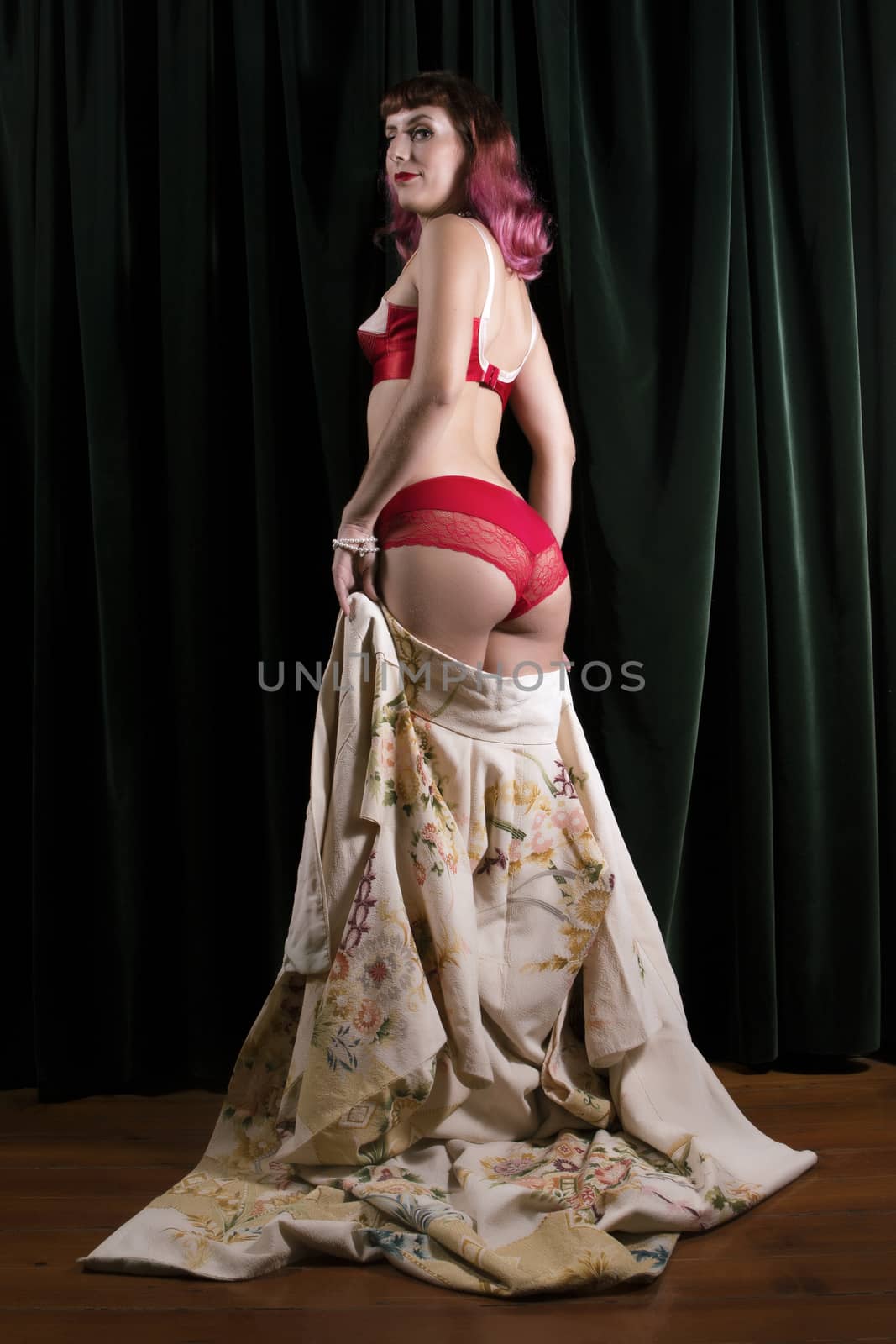 Girl with red vintage lingerie and kimono next to velvet curtains.