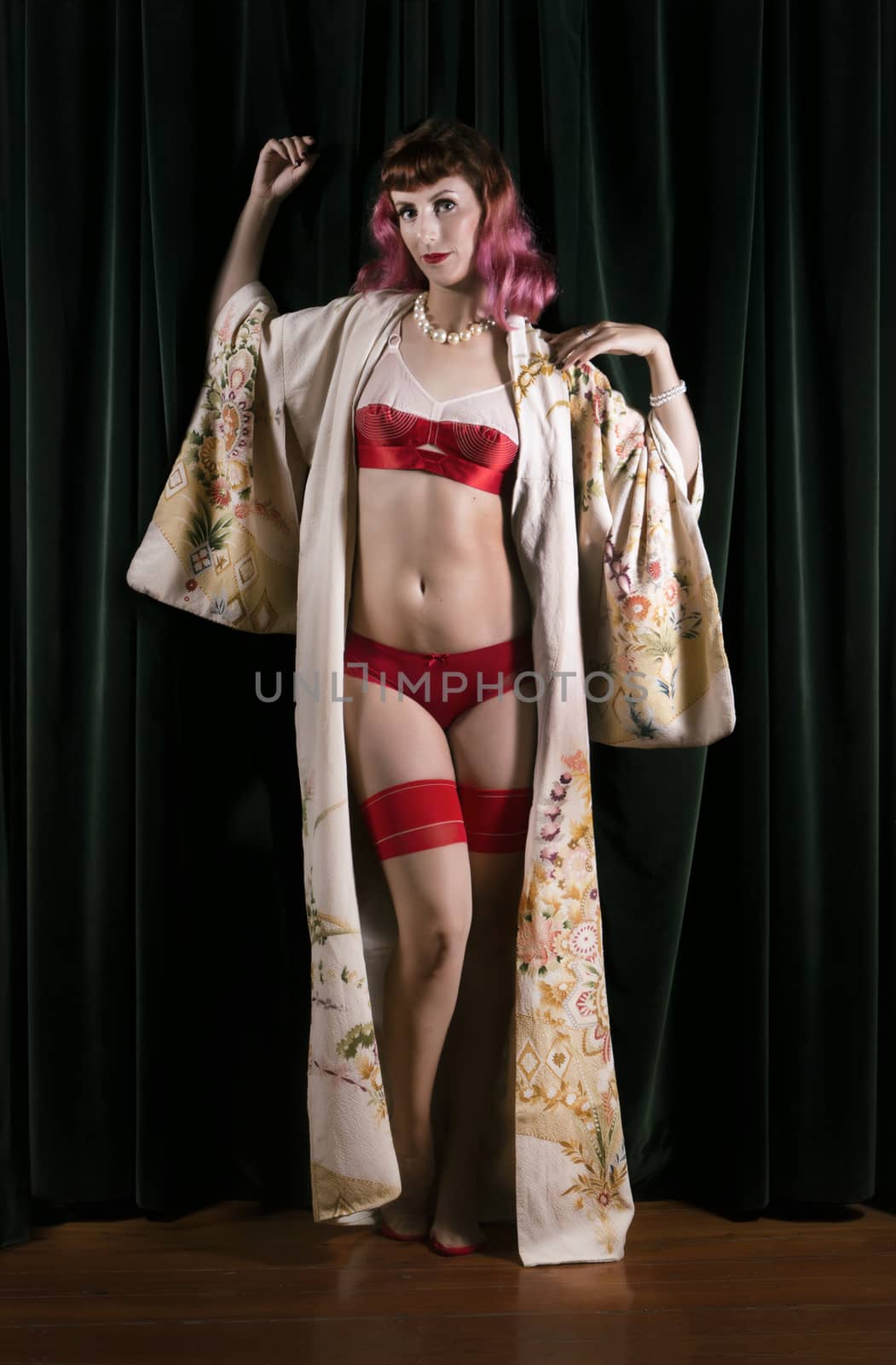Girl with red vintage lingerie and kimono next to velvet curtains.