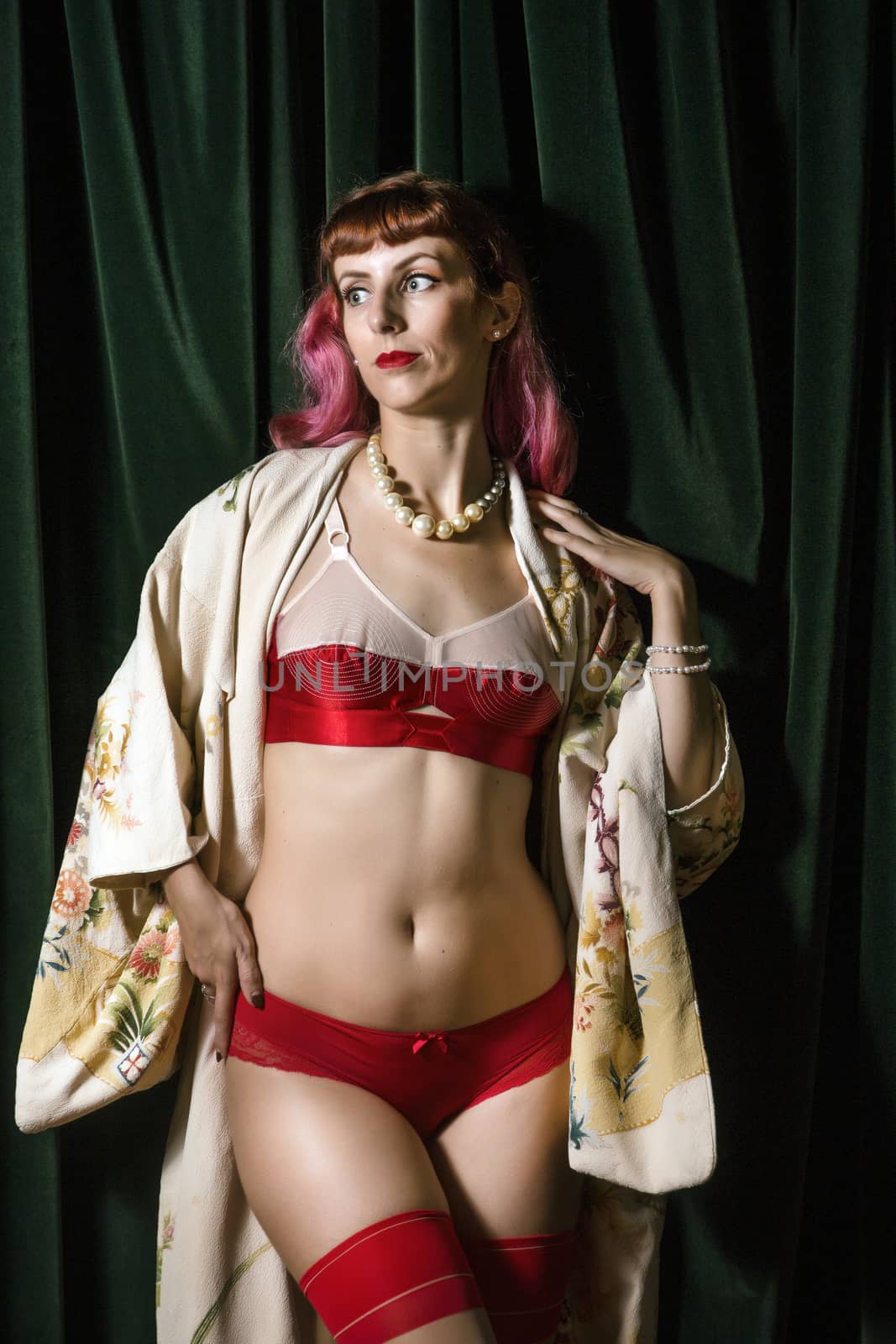 Girl with red vintage lingerie and kimono next to velvet curtains.