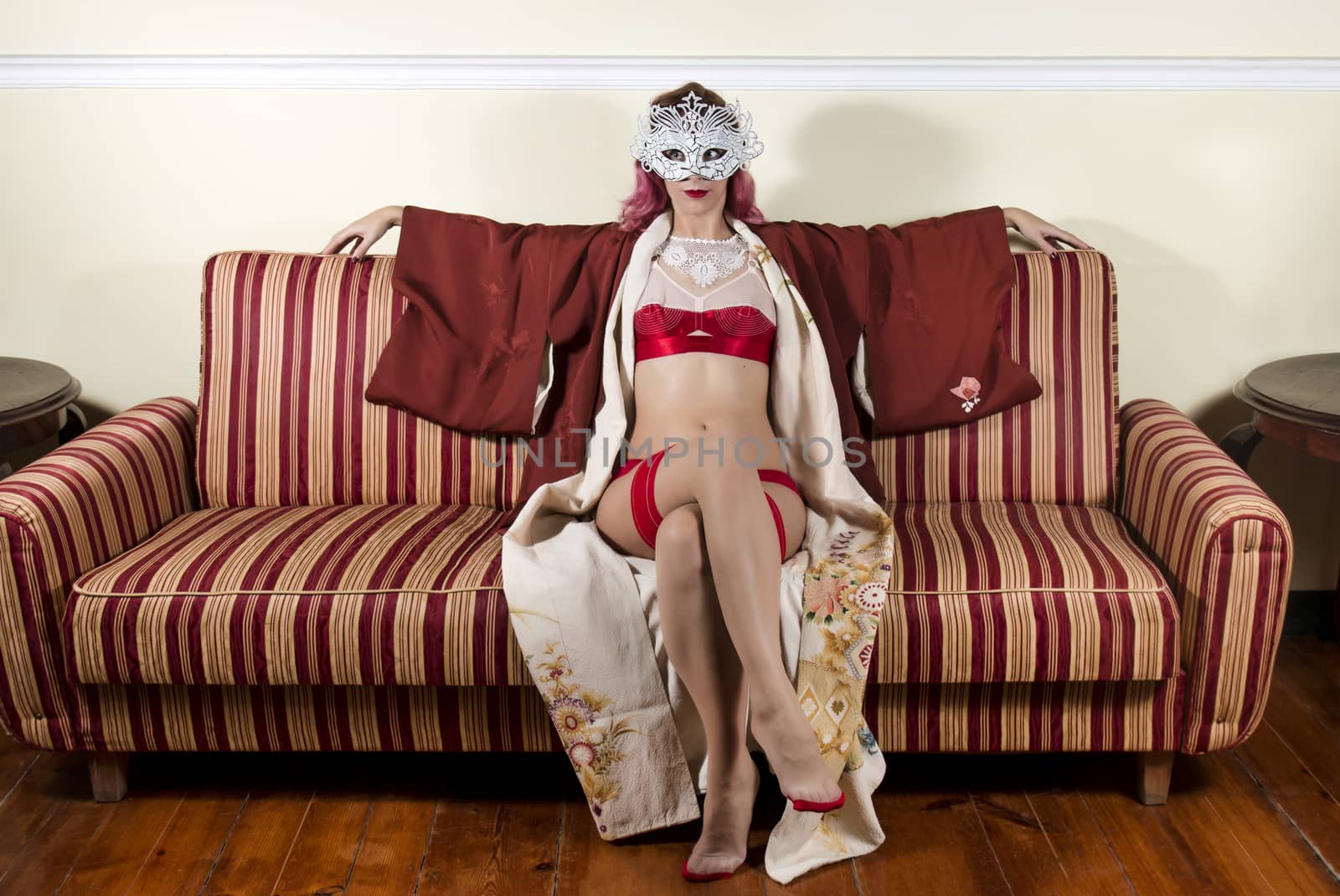 Girl with red vintage lingerie with a striped sofa in the living room.
