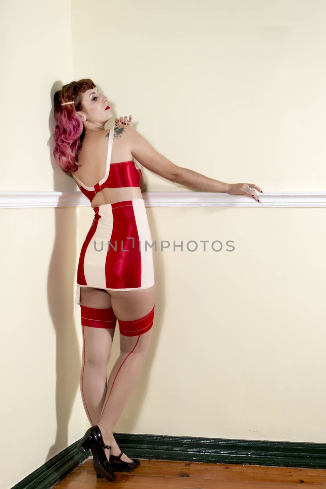 Girl with red vintage lingerie on the corner of a room.