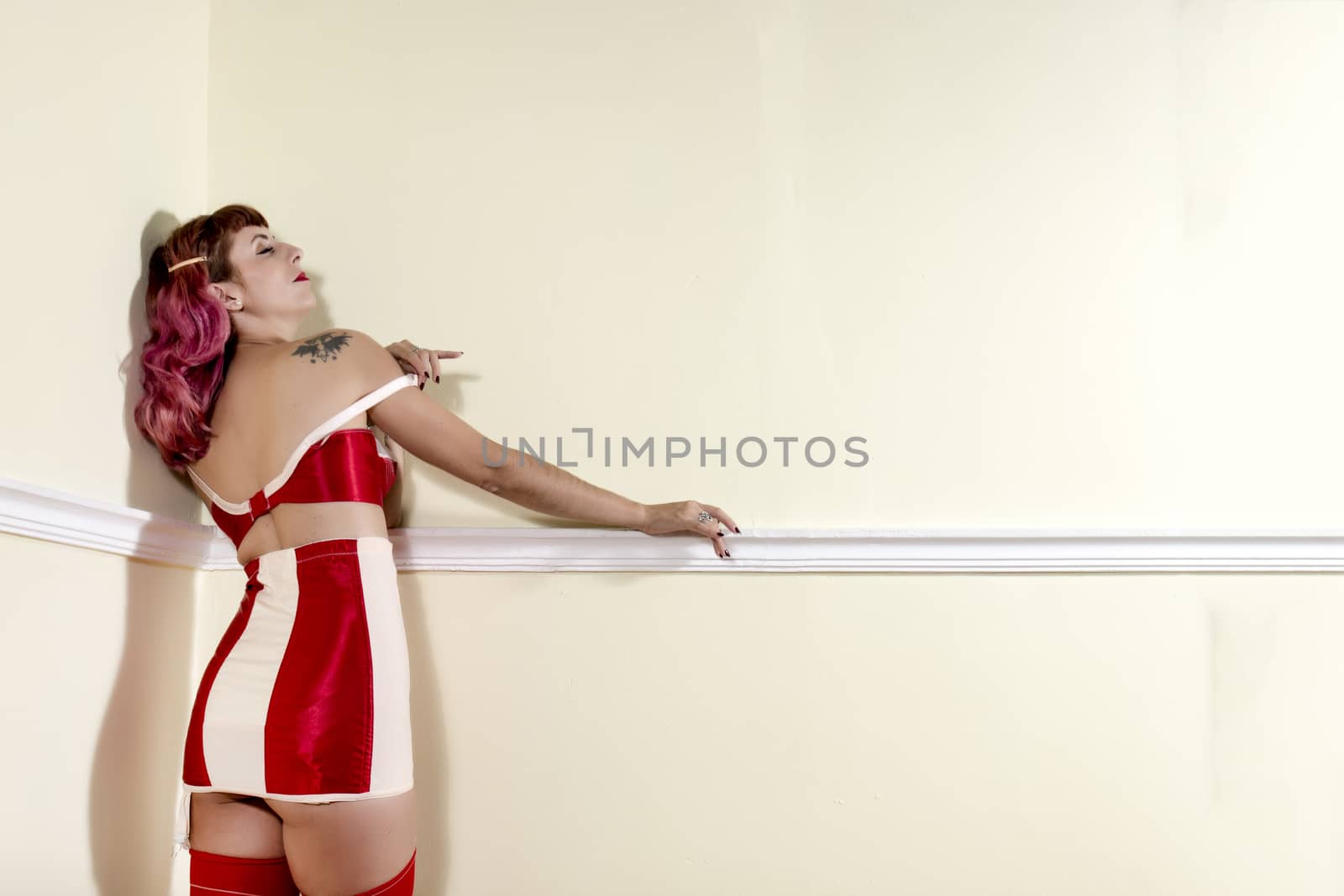 Girl with red vintage lingerie on the corner of a room.