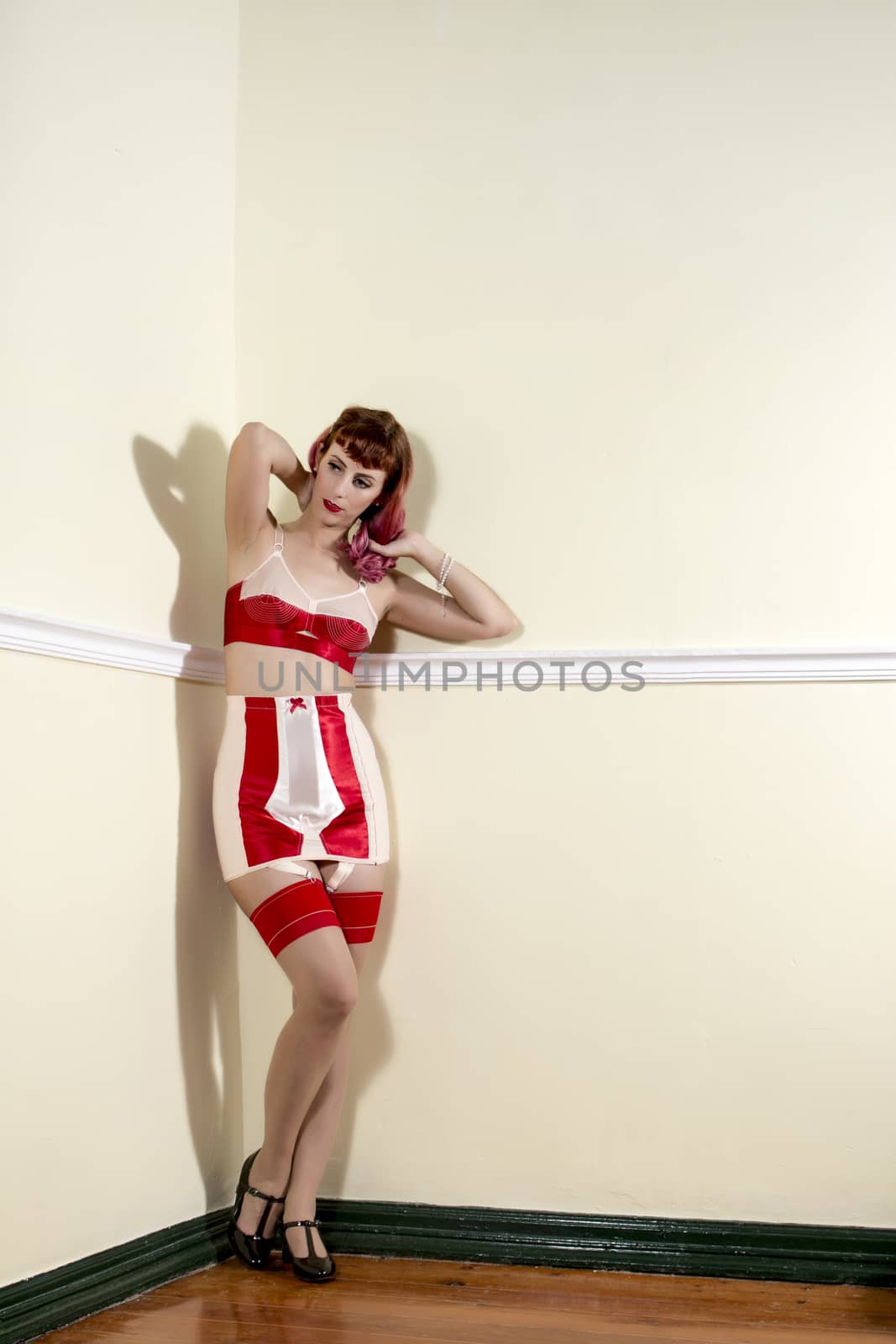 Girl with red vintage lingerie on the corner of a room.