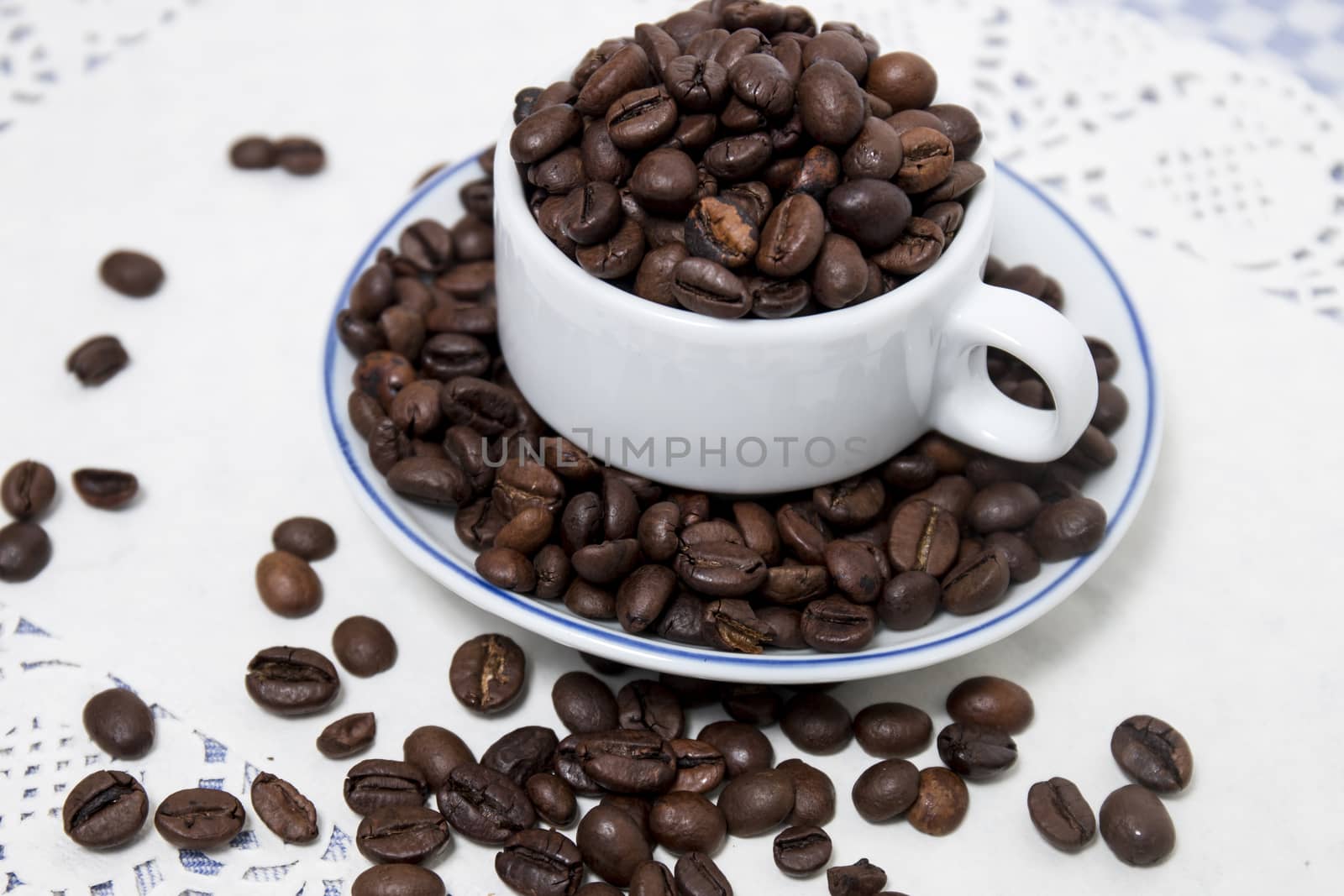 Composition of a cup full of coffee beans on table.