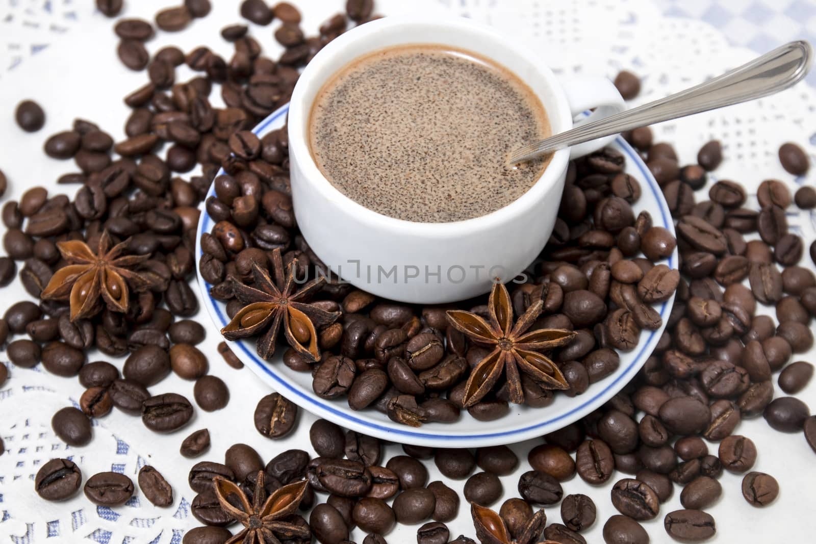 Composition of a coffee cup with spreaded beans and star anise.