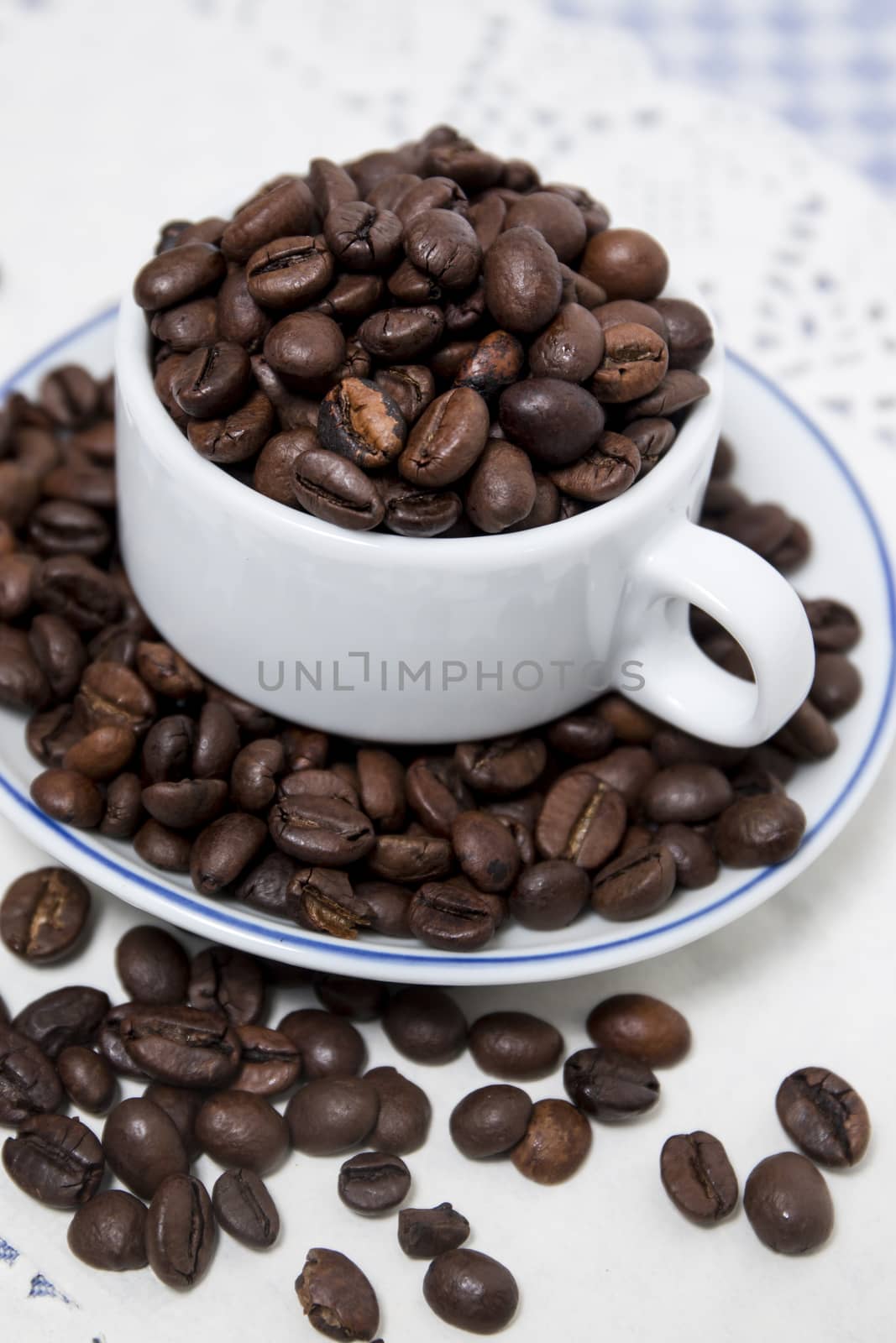 Composition of a cup full of coffee beans on table.