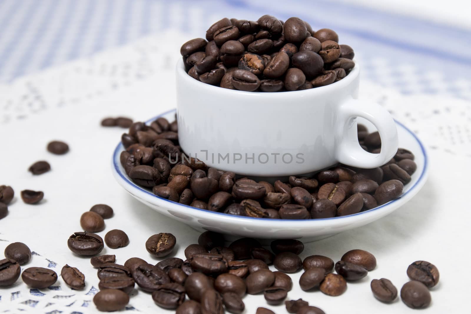 Composition of a cup full of coffee beans on table.