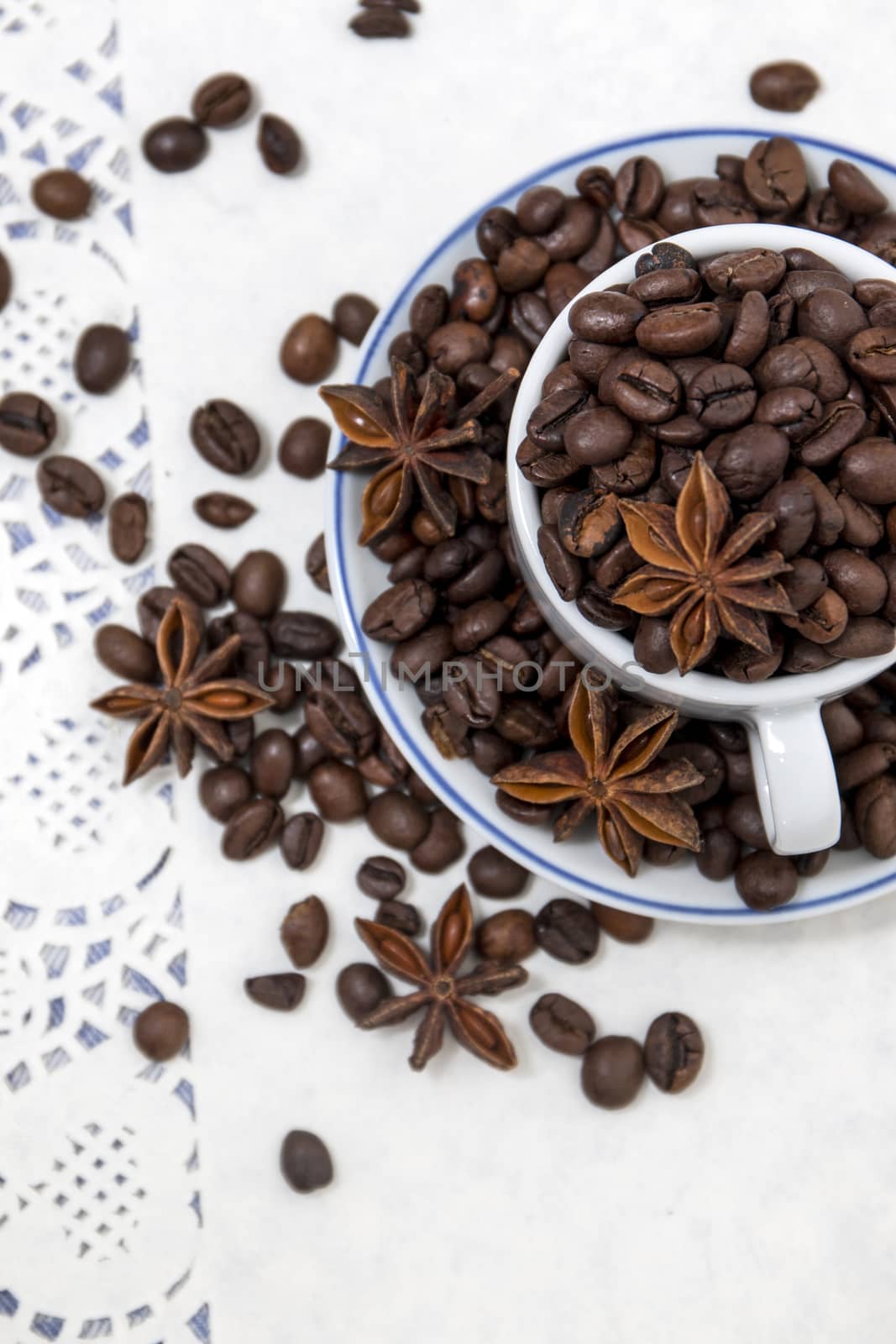 Composition of a cup full of coffee beans on table.
