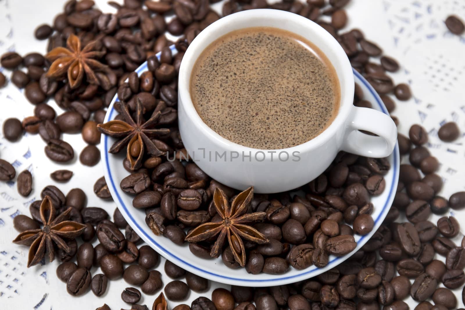 Composition of a coffee cup with spreaded beans and star anise.