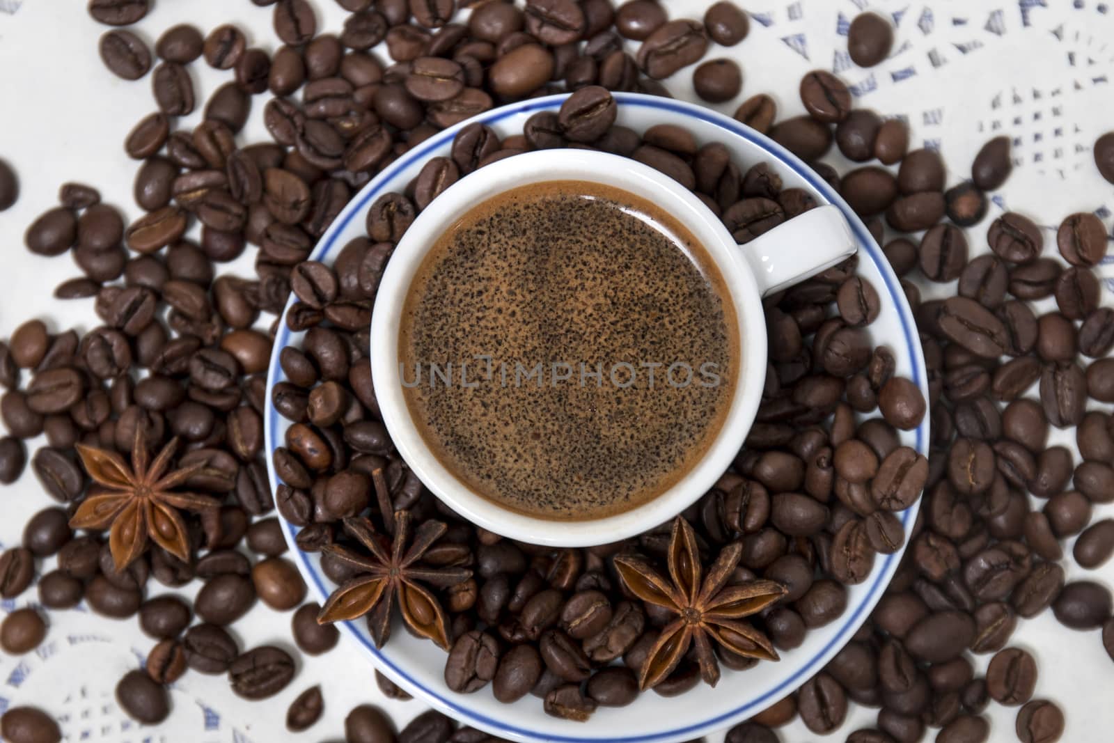 Composition of a coffee cup with spreaded beans and star anise.