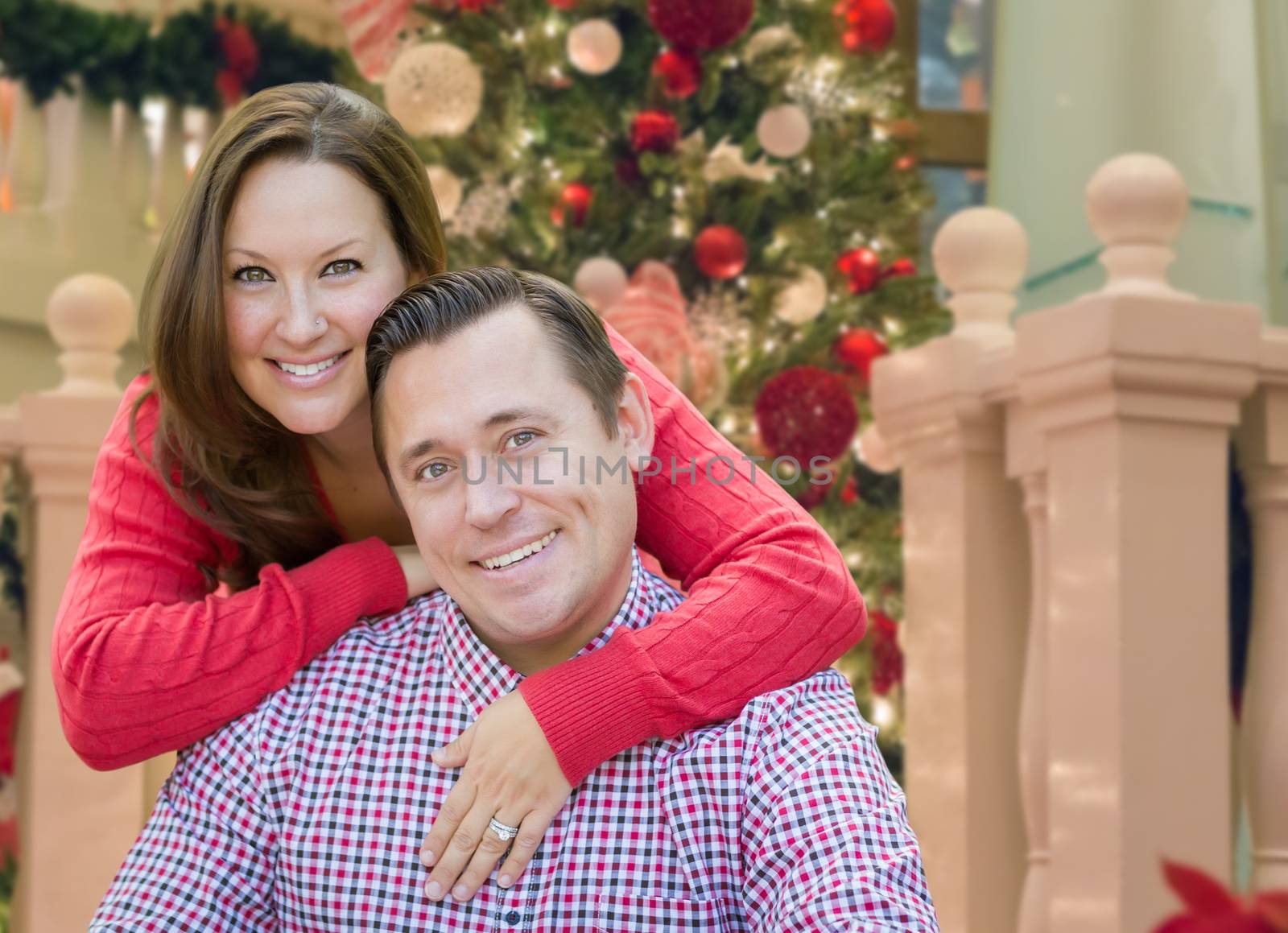 Caucasian Couple Hugging In Front of Decorated Christmas Tree. by Feverpitched