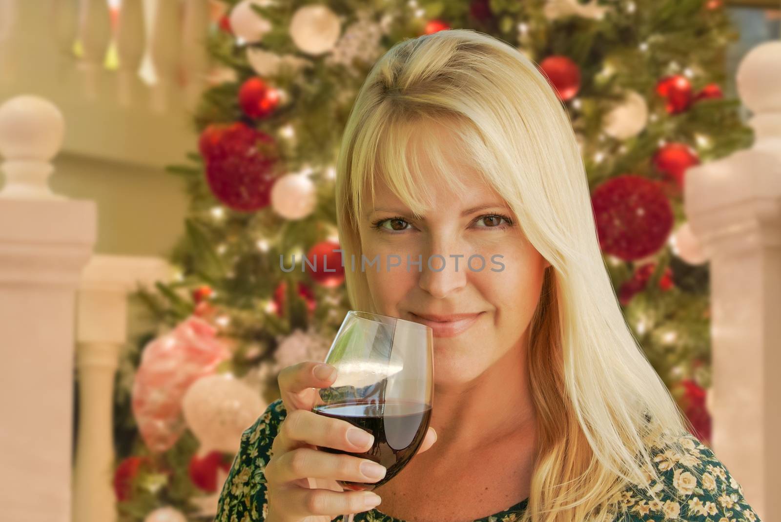 Blond Woman with Wine Glass In Front of Decrated Christmas Tree.