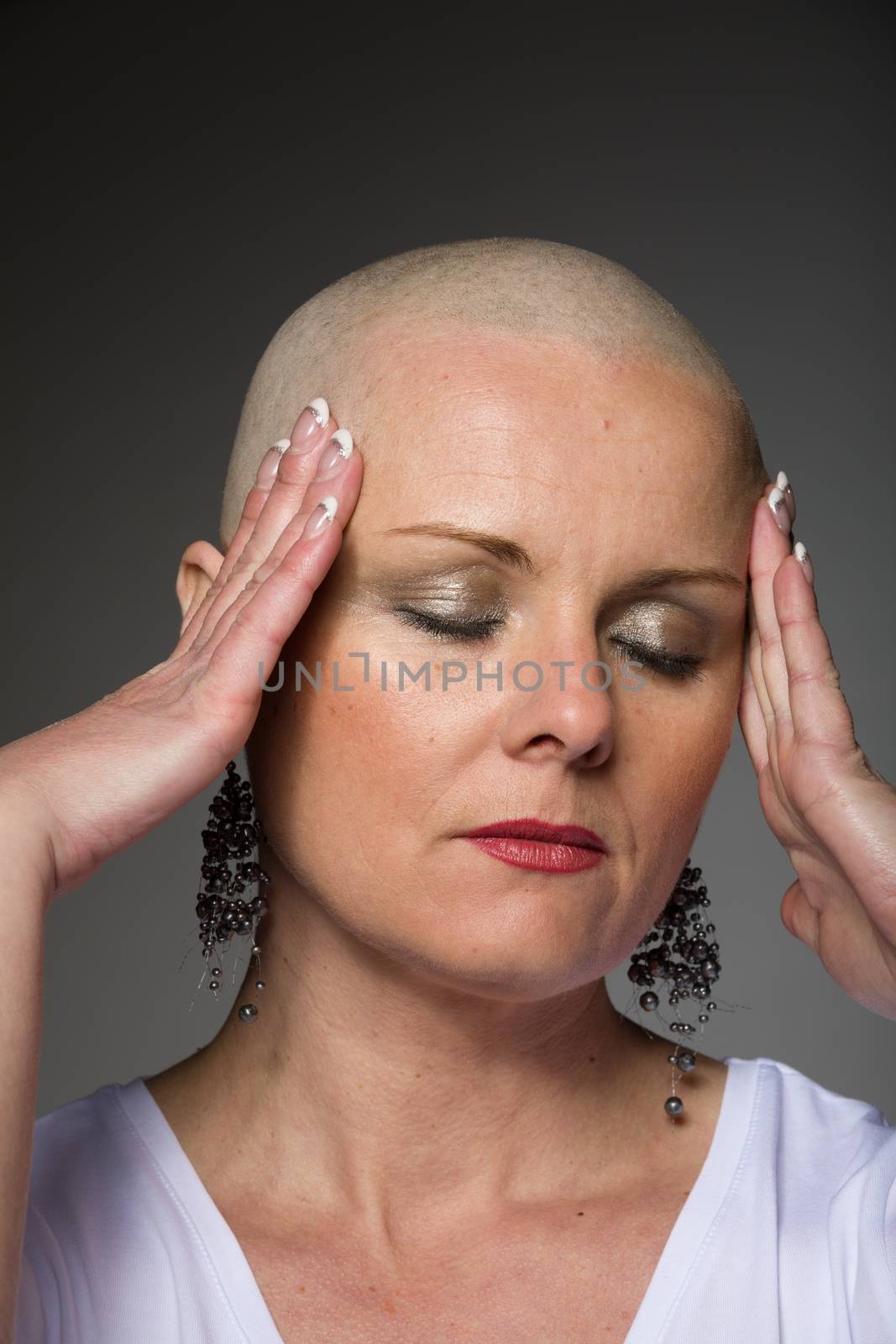 Portrait of beautiful middle age woman sad patient with cancer with shaved head without hair, hope in healing. Woman holding her head