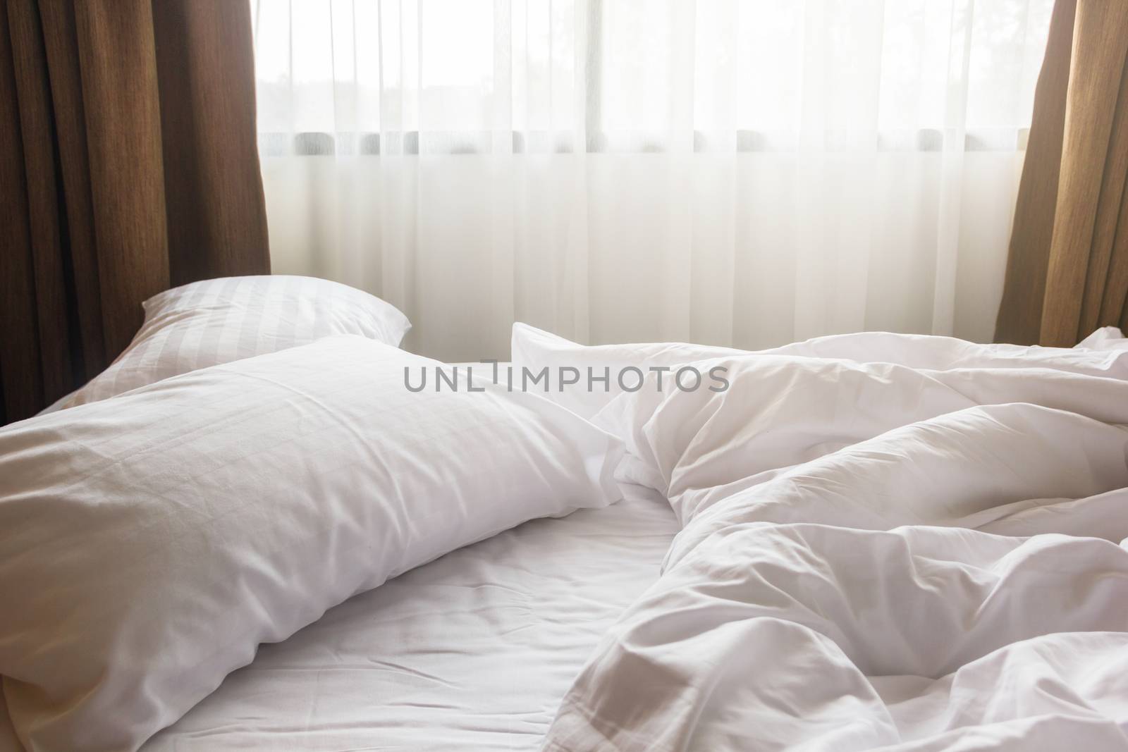 white pillow and blanket with wrinkle messy on bed in bedroom, messy from sleeping in a long night winter.