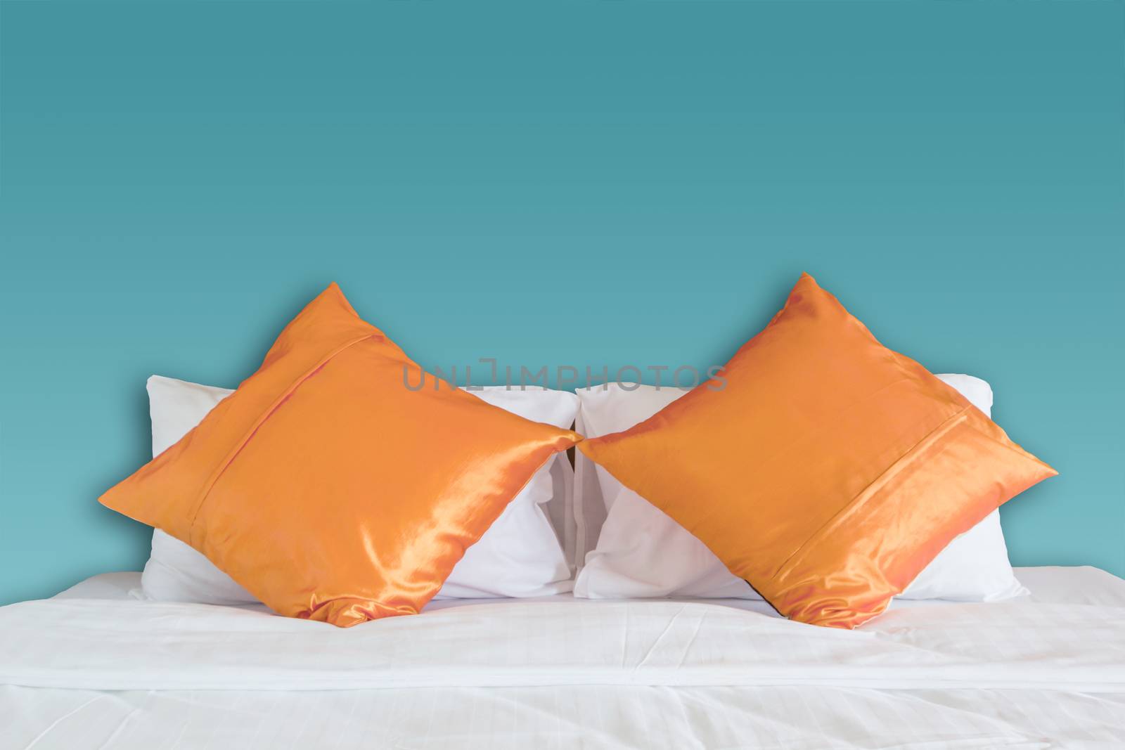 blue wall and orange pillow on white bed by rakoptonLPN