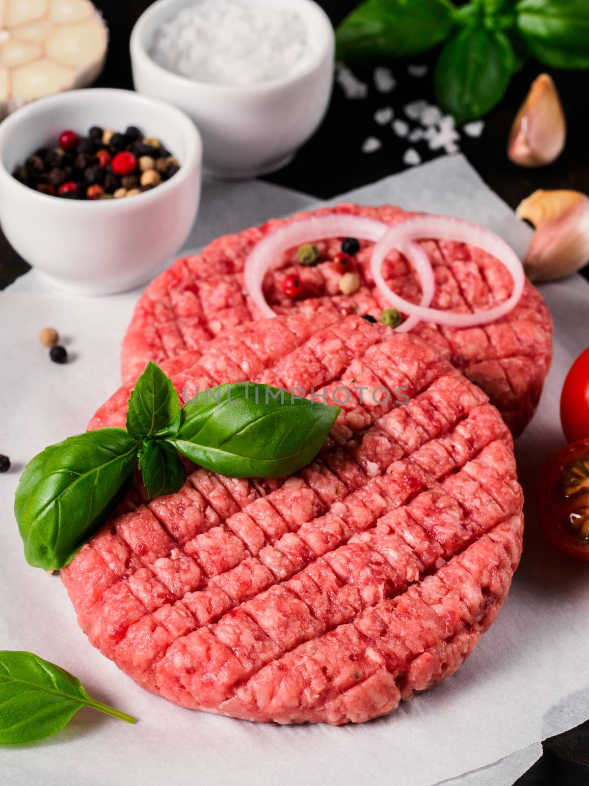 Close up view of two raw meat steak cutlets for burger with vegetables by fascinadora