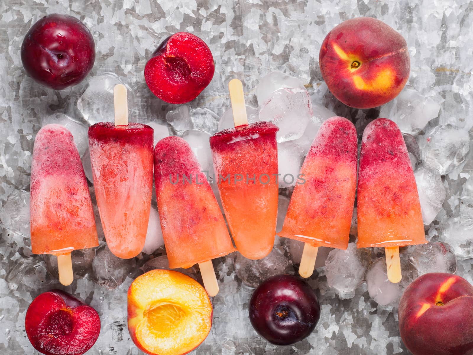 top view of plum and peach popsicle on gray metal background. Fruit popsicles ice cream with fresh plums and peach.