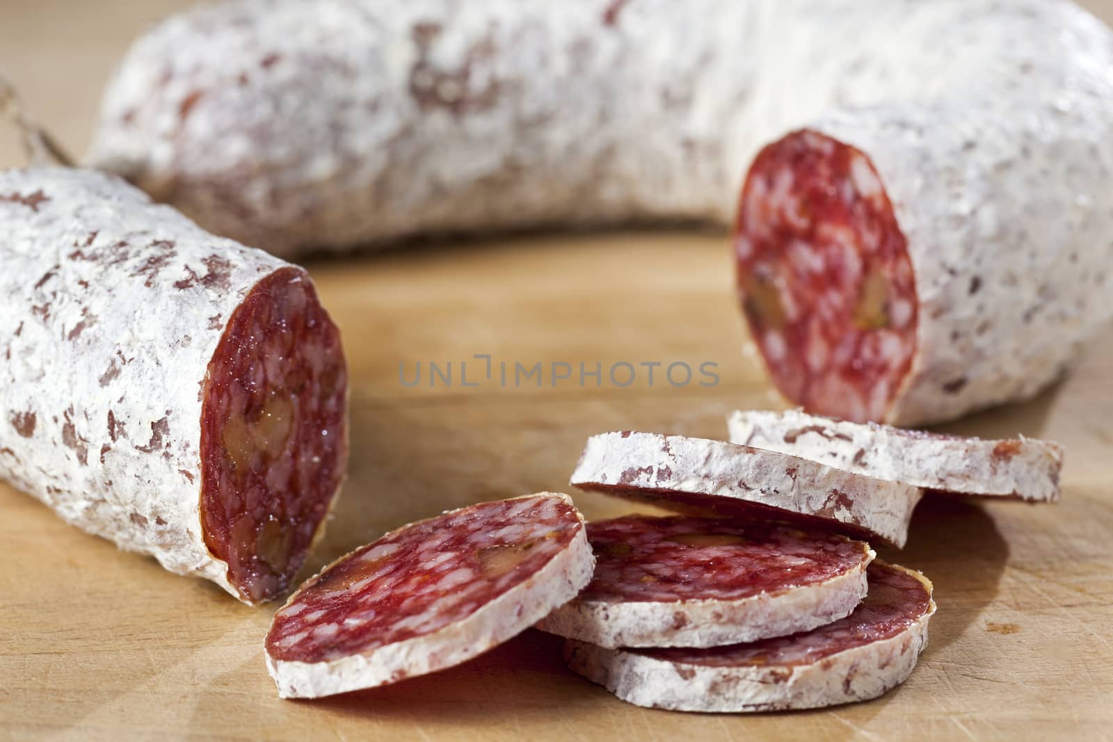 Closeup of a delicious dry sausage with walnuts on wood