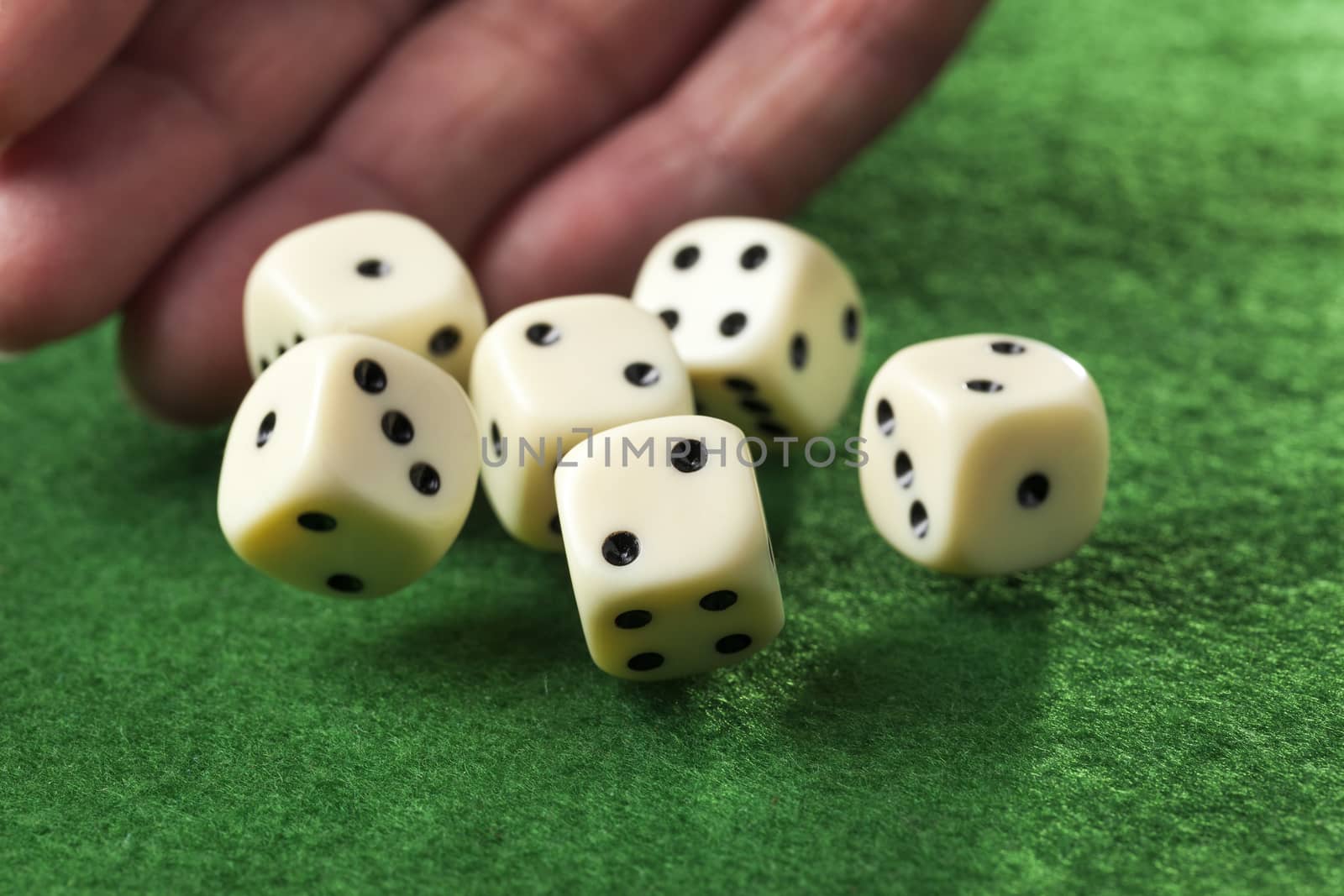 Hand throwing dices on green felt