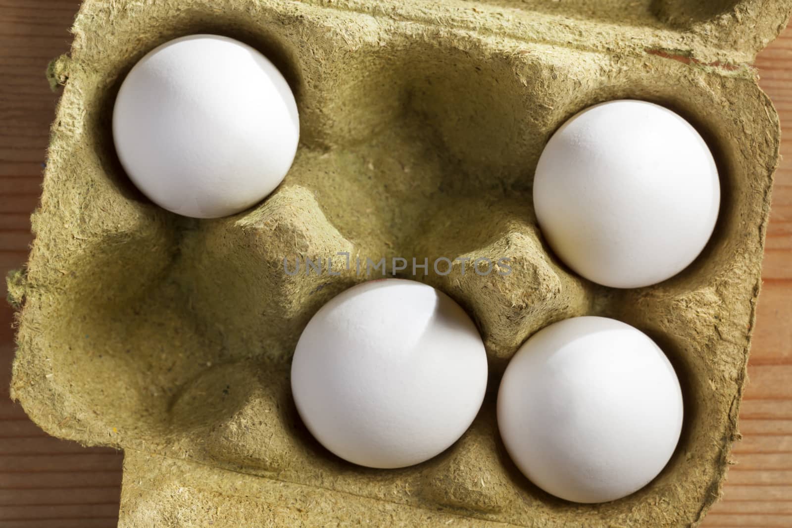 Four white organic eggs in a box consisting 50 percent grass fibers and is fully recyclable.