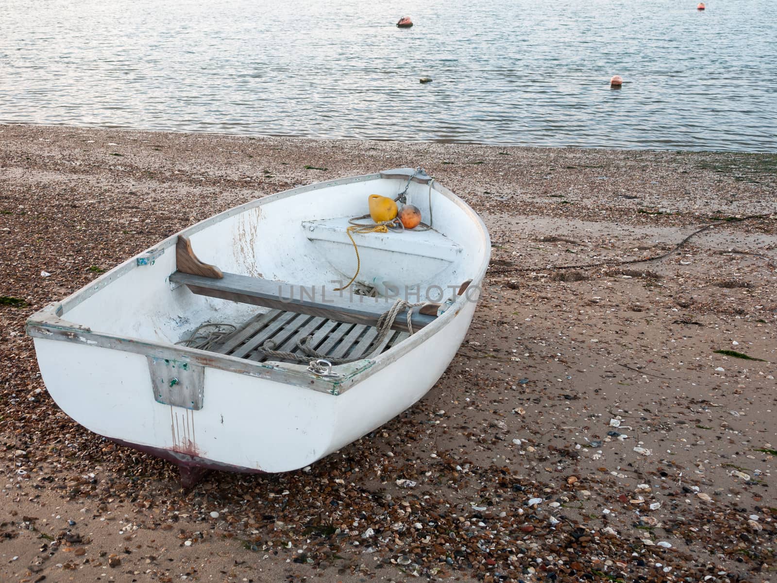 small white private boat parked moored on beach front bay  by callumrc