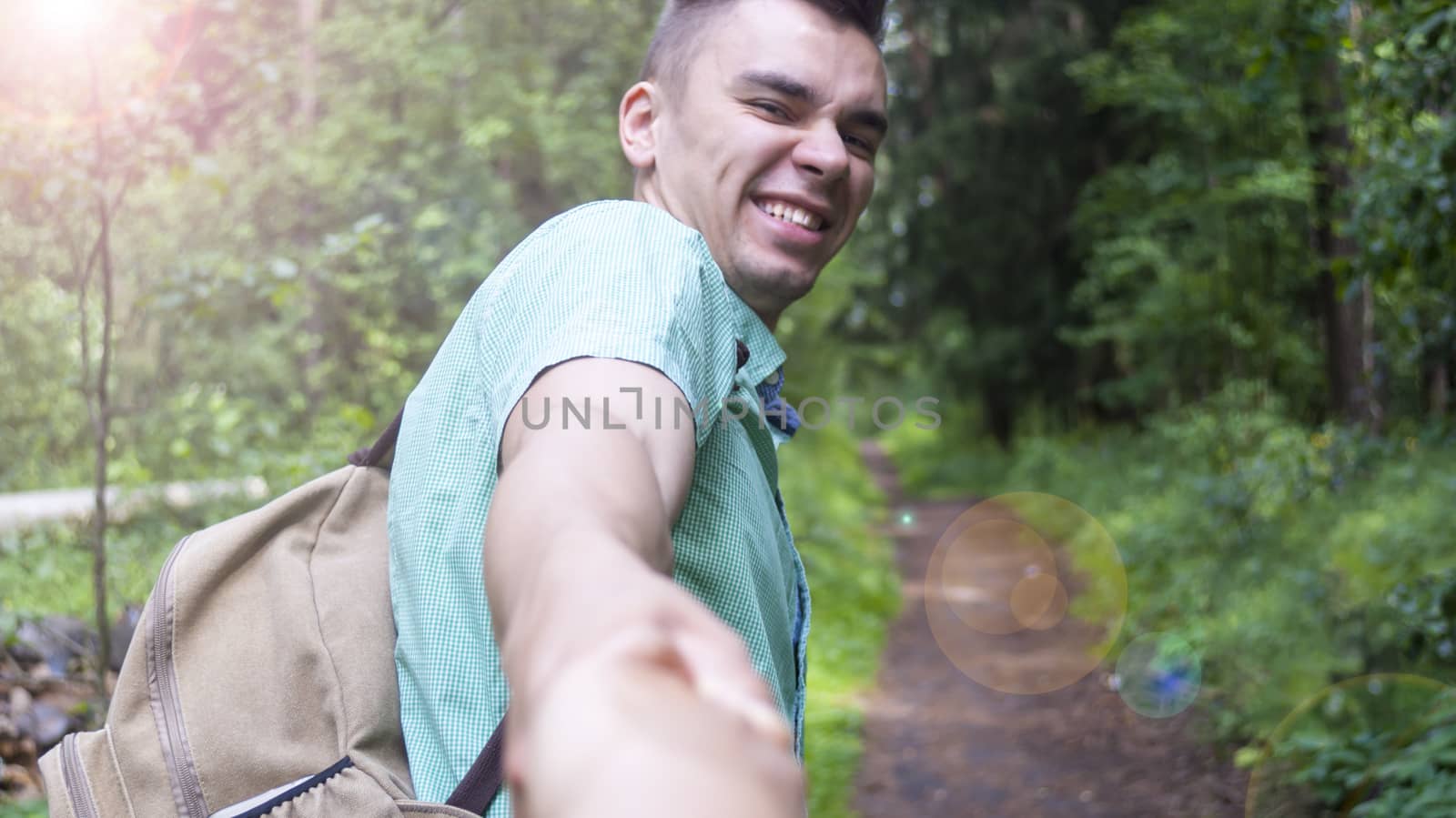 The young man pulls the girl's hand on the forest path
