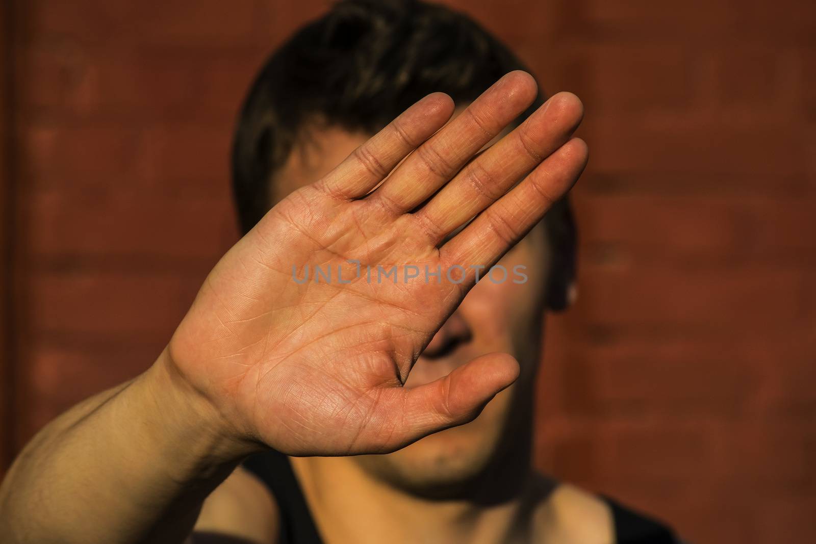 a young man covers his face with hand