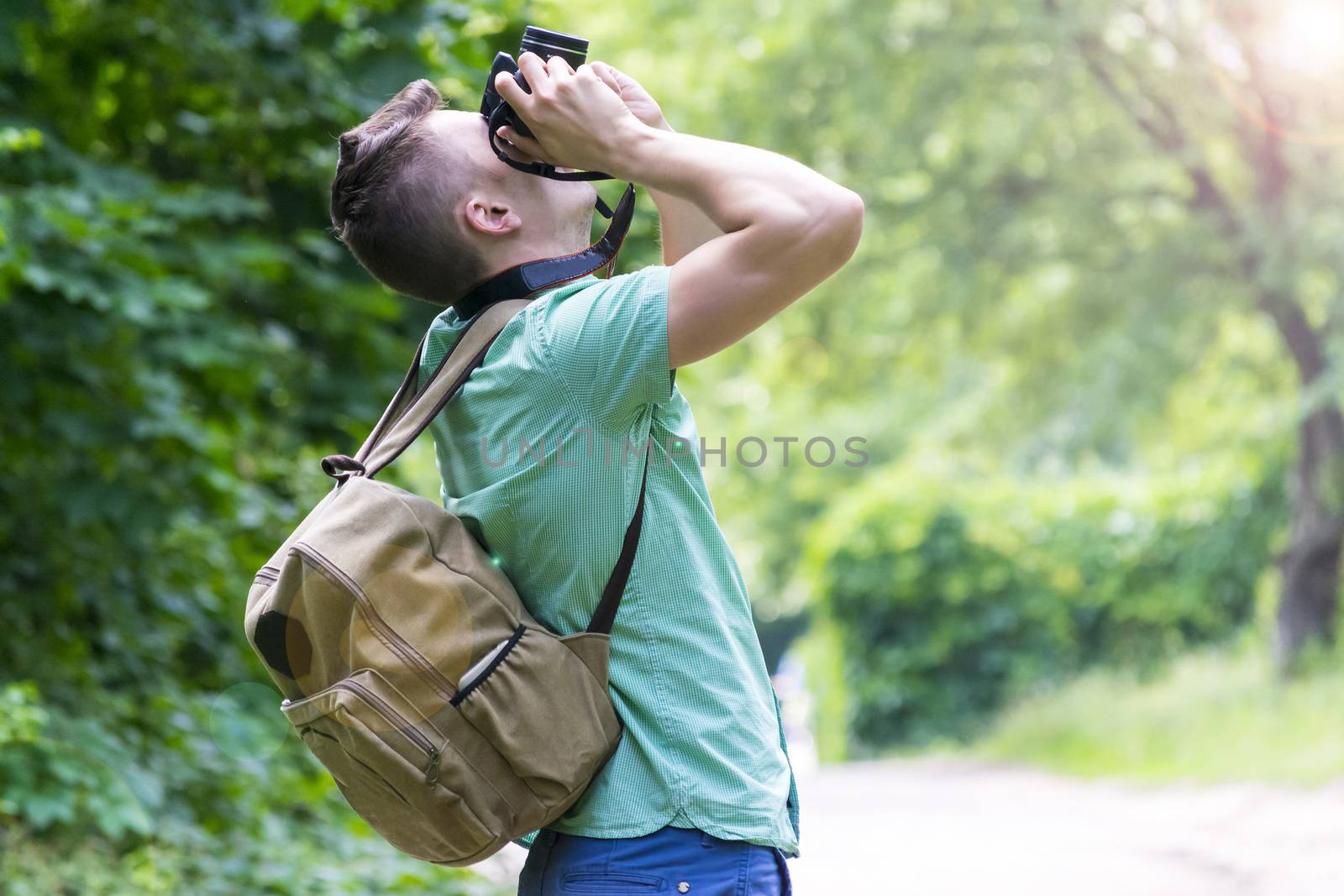 A young man takes photos of nature in the woods