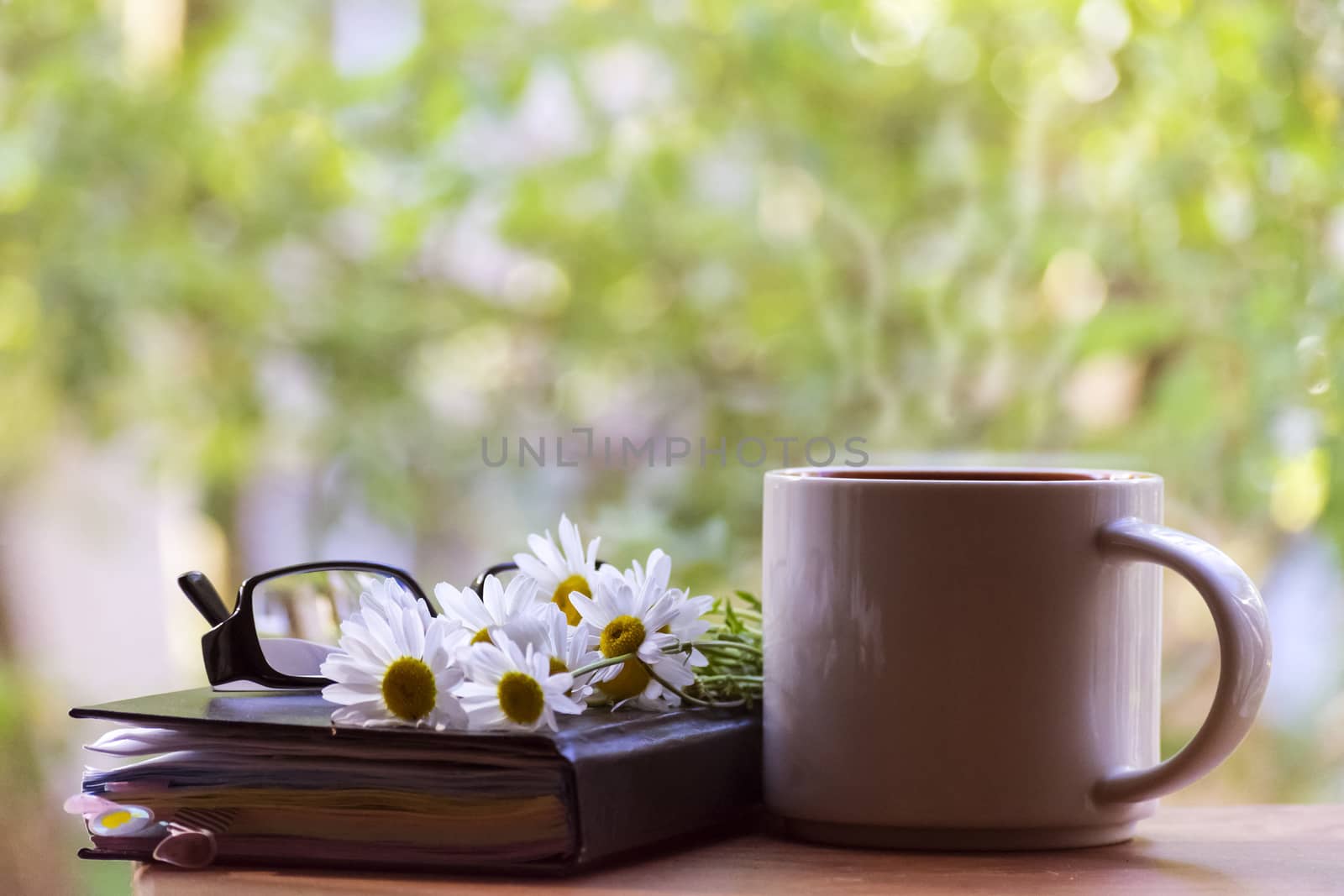 Mug, daisies, Notepad, glasses. The concept of a Sunny summer morning.