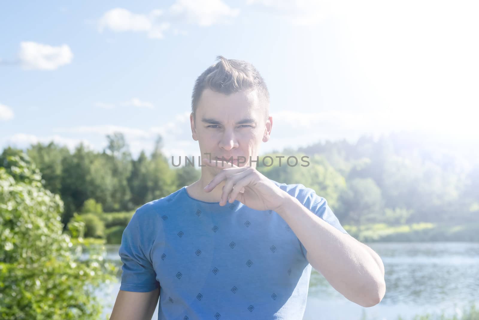 The young man in the background of the pond. Summer. Portrait.