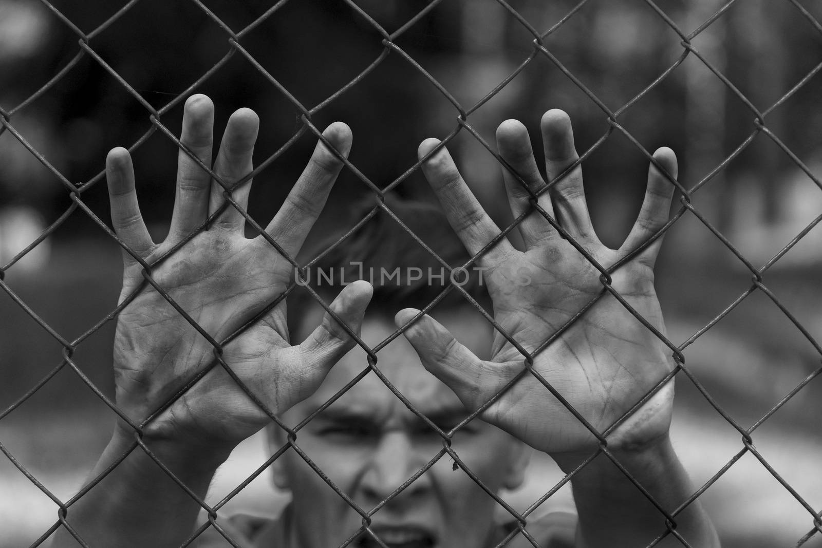 A young man behind bars. Imprisonment, famine, war.