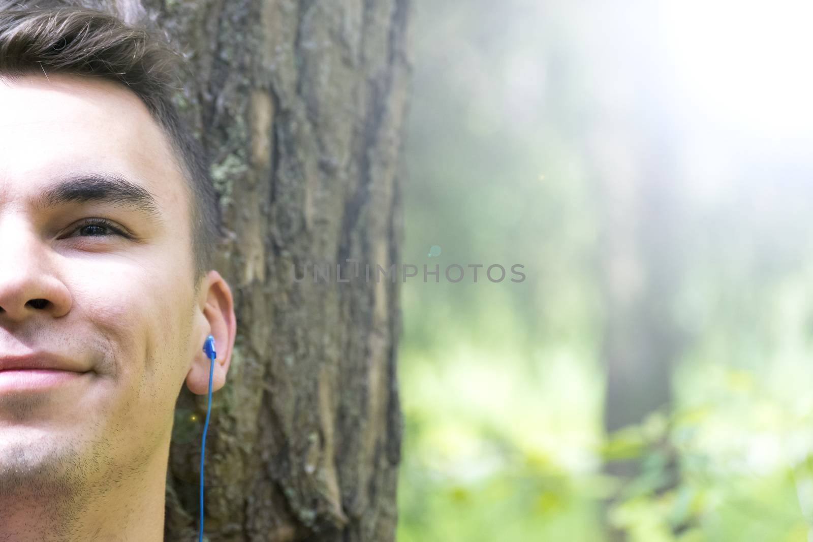 A young man sits under a tree and listens to music