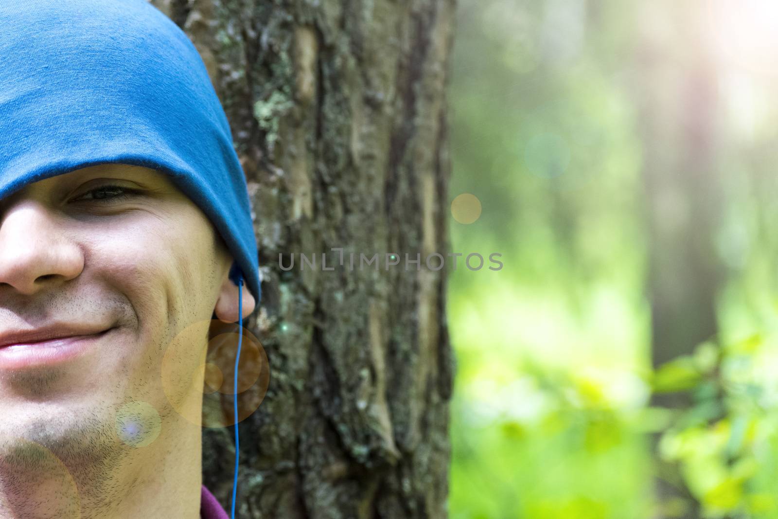 A young man sits under a tree and listens to music