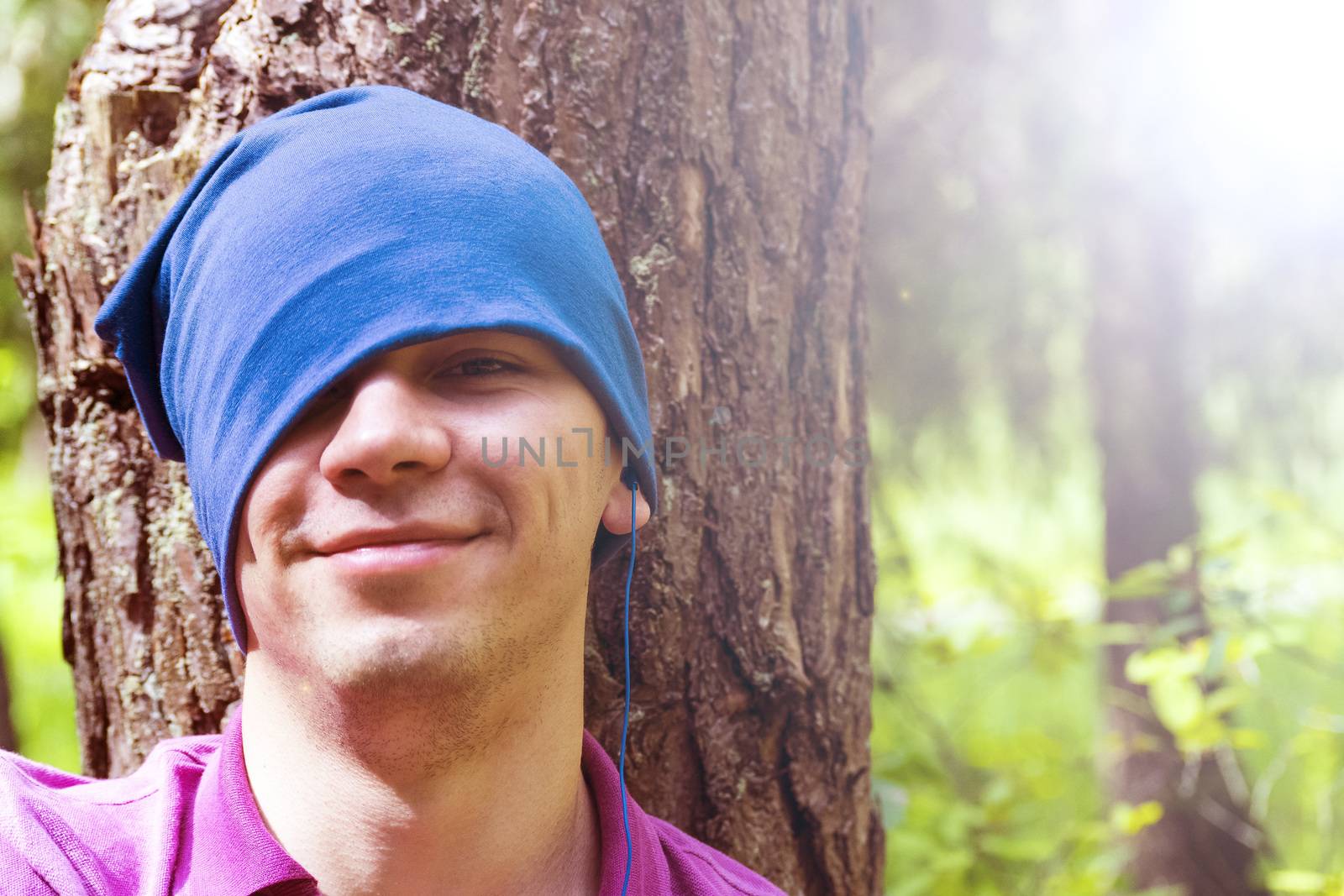 A young man sits under a tree and listens to music