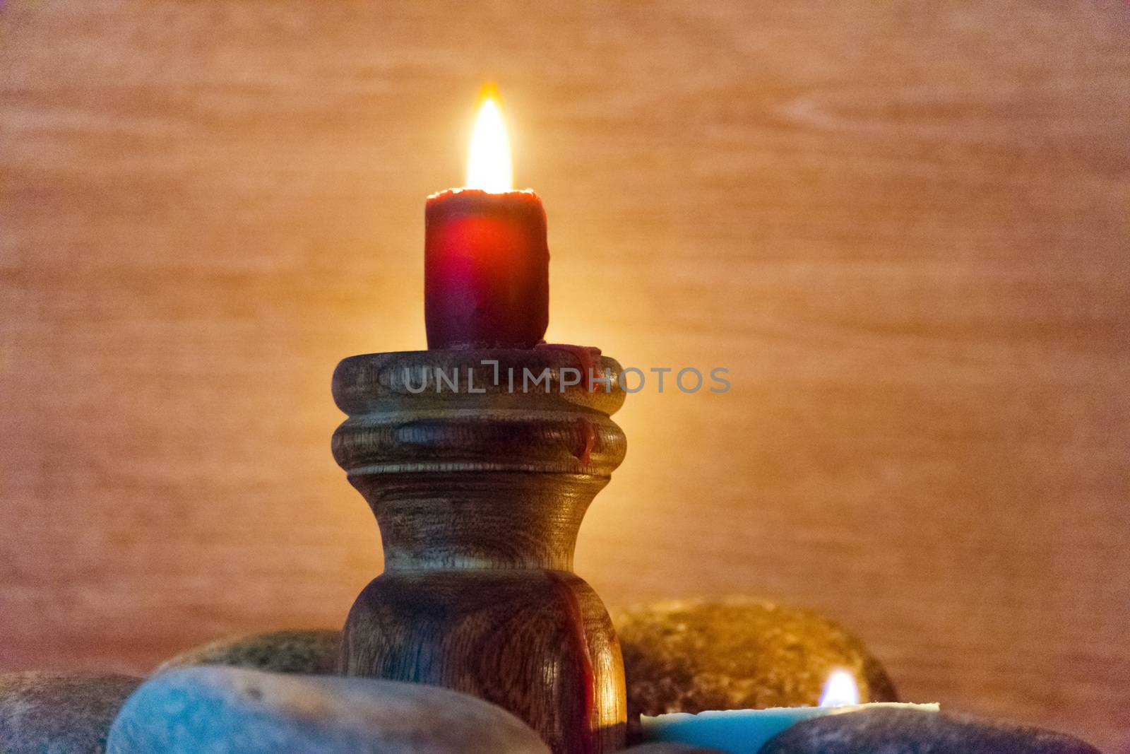 Several multi-colored candles are lit and surrounded by stones.