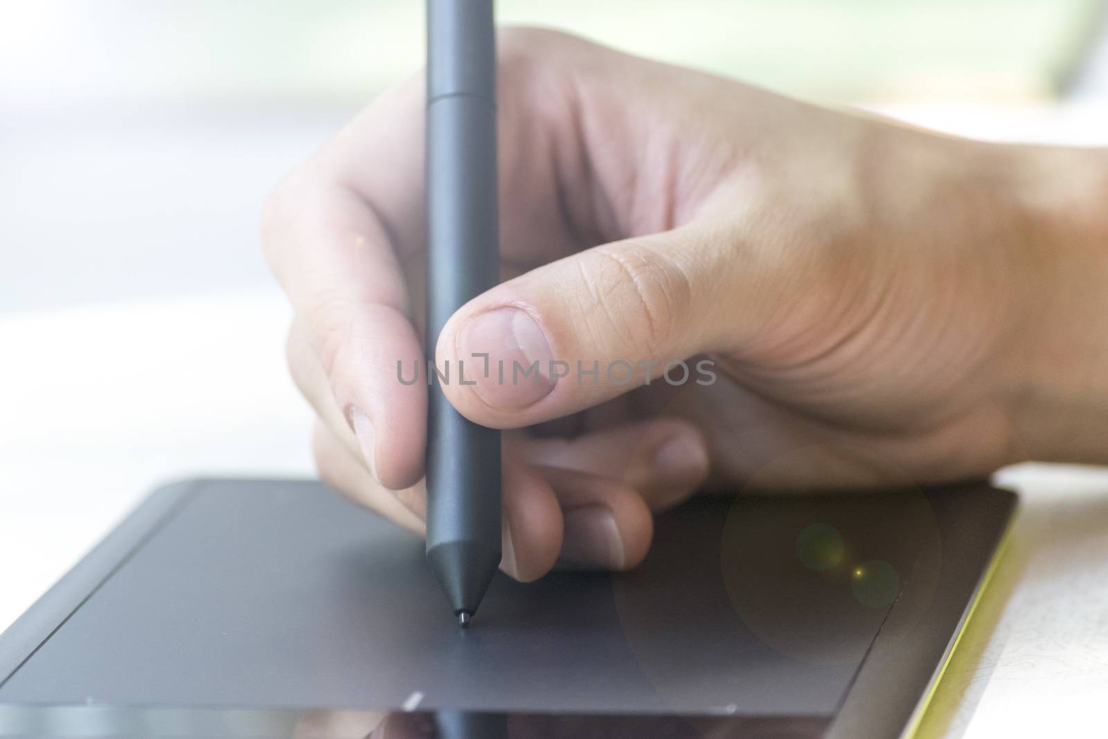 Hand of a young man writes on a graphics tablet