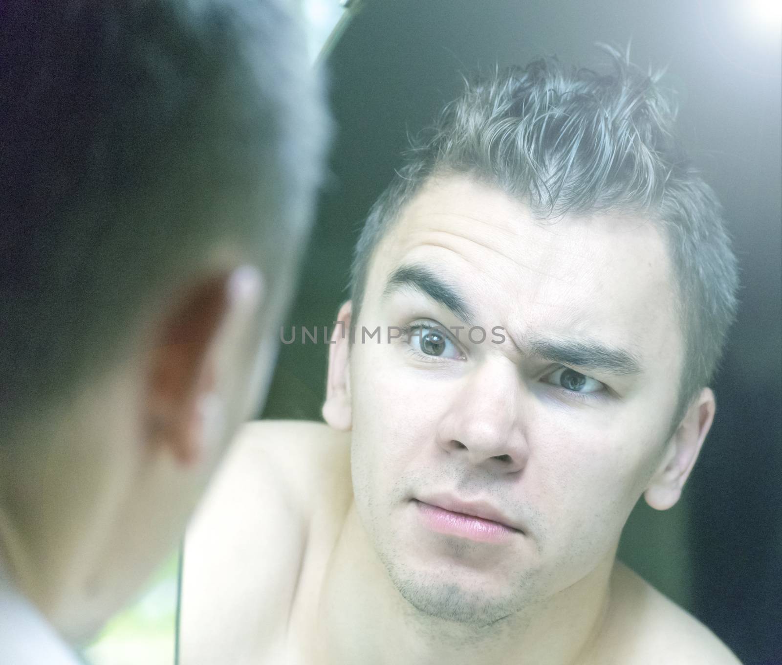 The young man looks at himself in the mirror