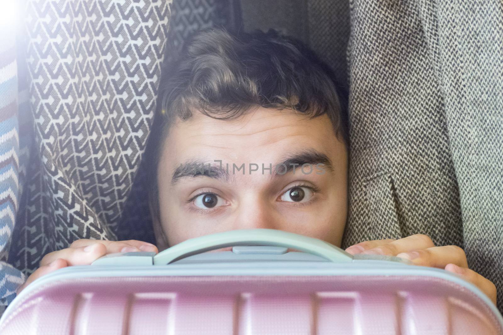 A young man hides in a closet covering yourself with a suitcase