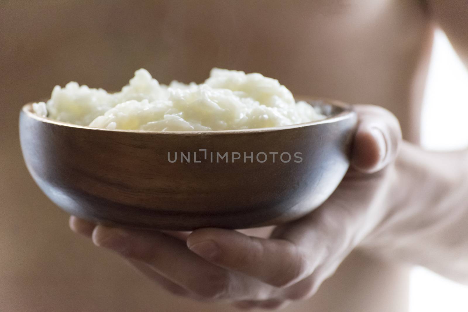 A young man holding a wooden bowl of rice porridge. The concept of a healthy Breakfast.