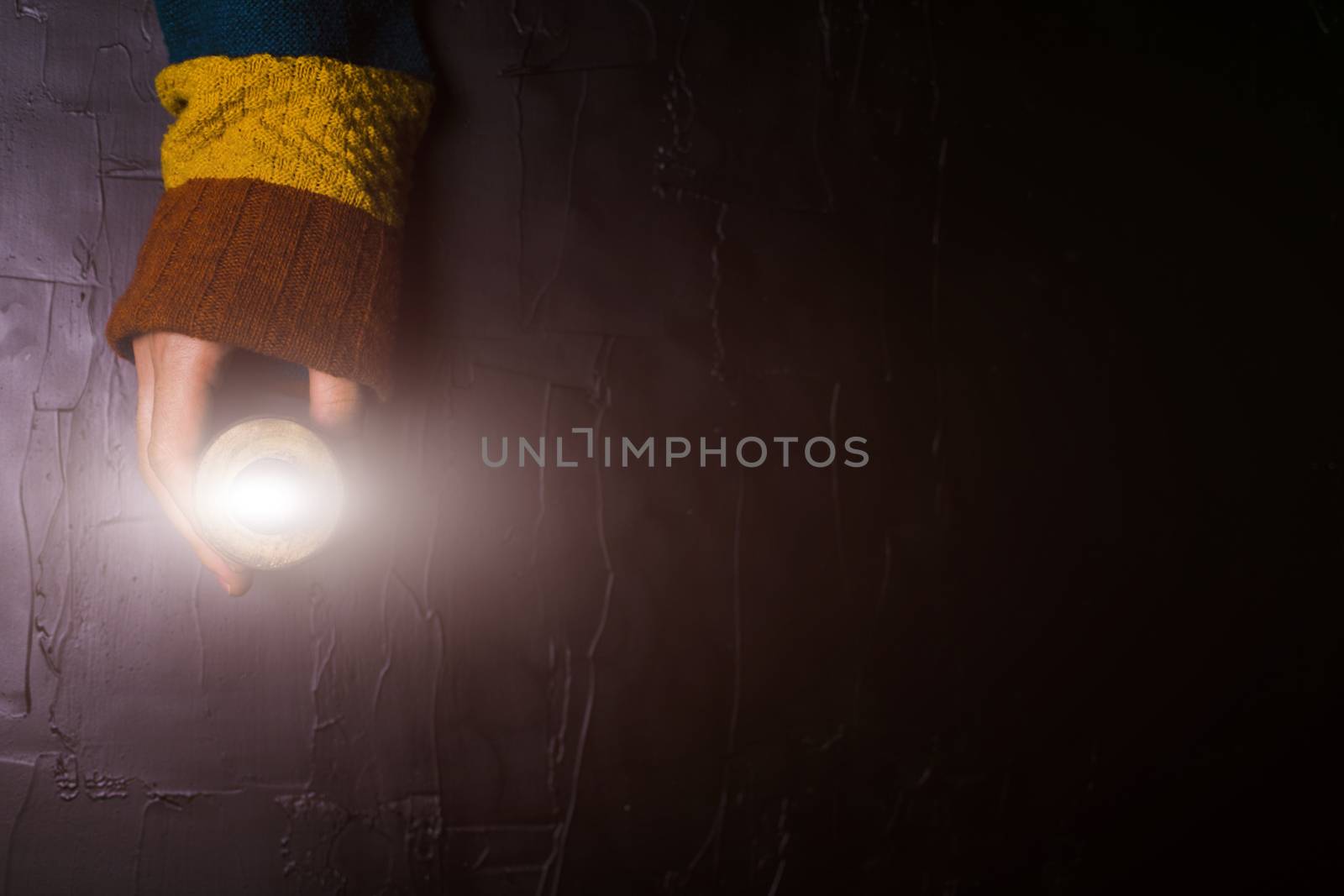 Male hand holds out a candle on a black background