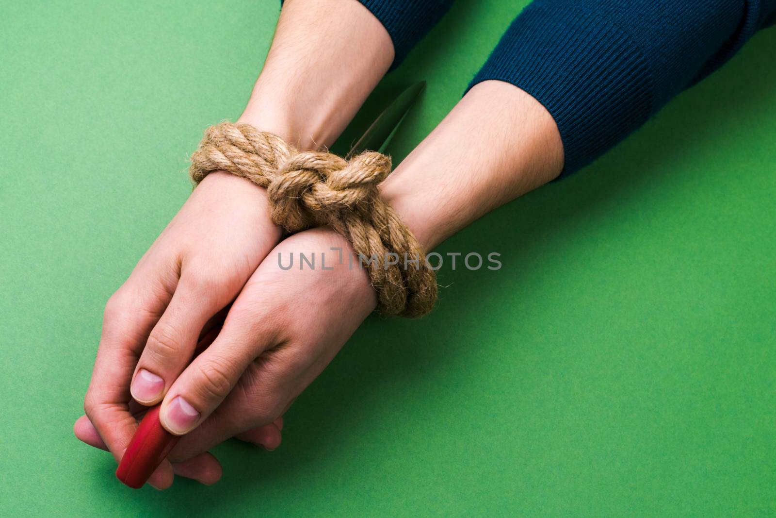 The man with bound hands and knife on green background
