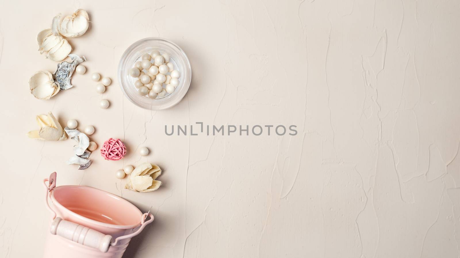 Decorative pail, blush, dry grass, pink ball. Still life in pastel color.